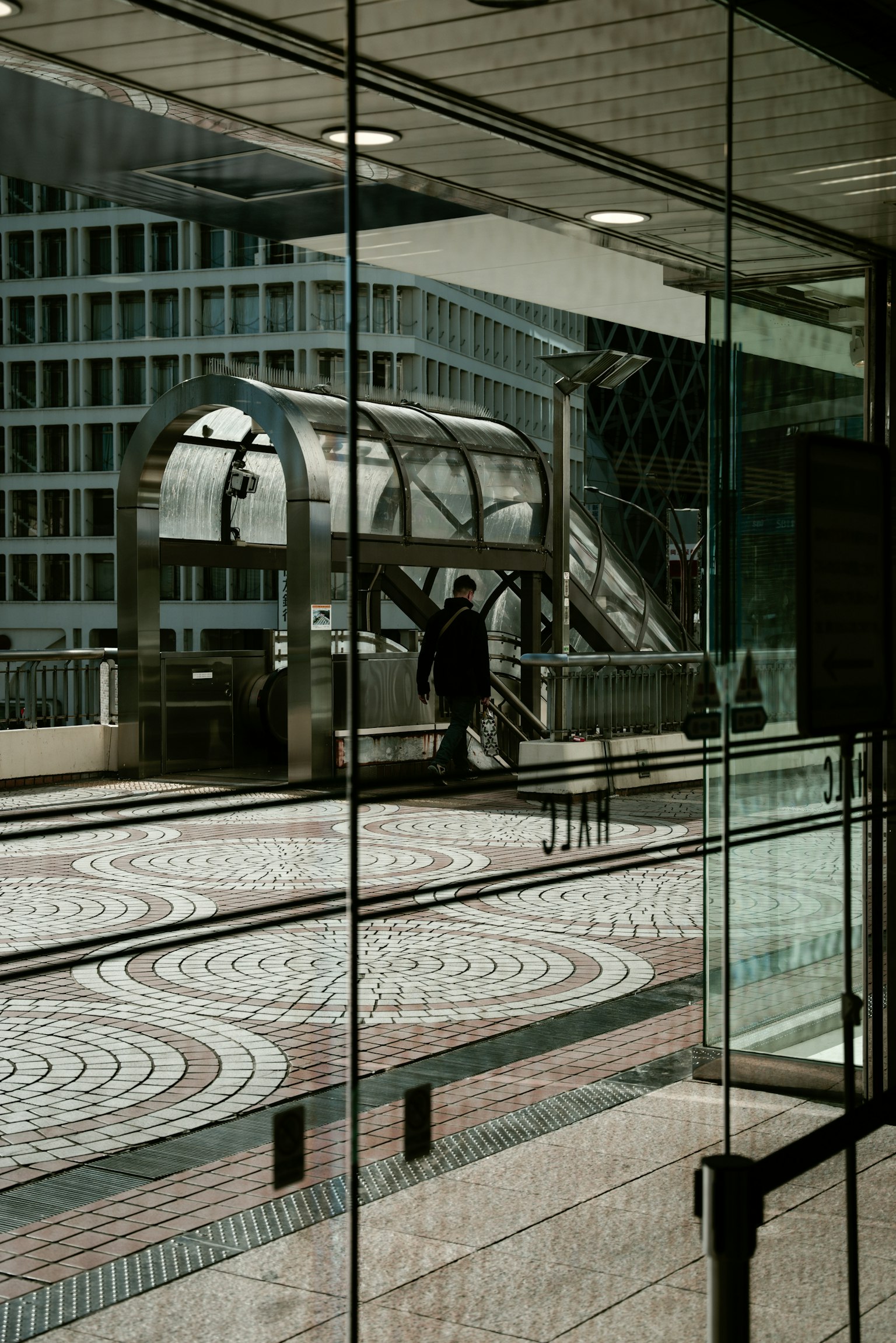 City train station viewed through glass featuring modern escalator