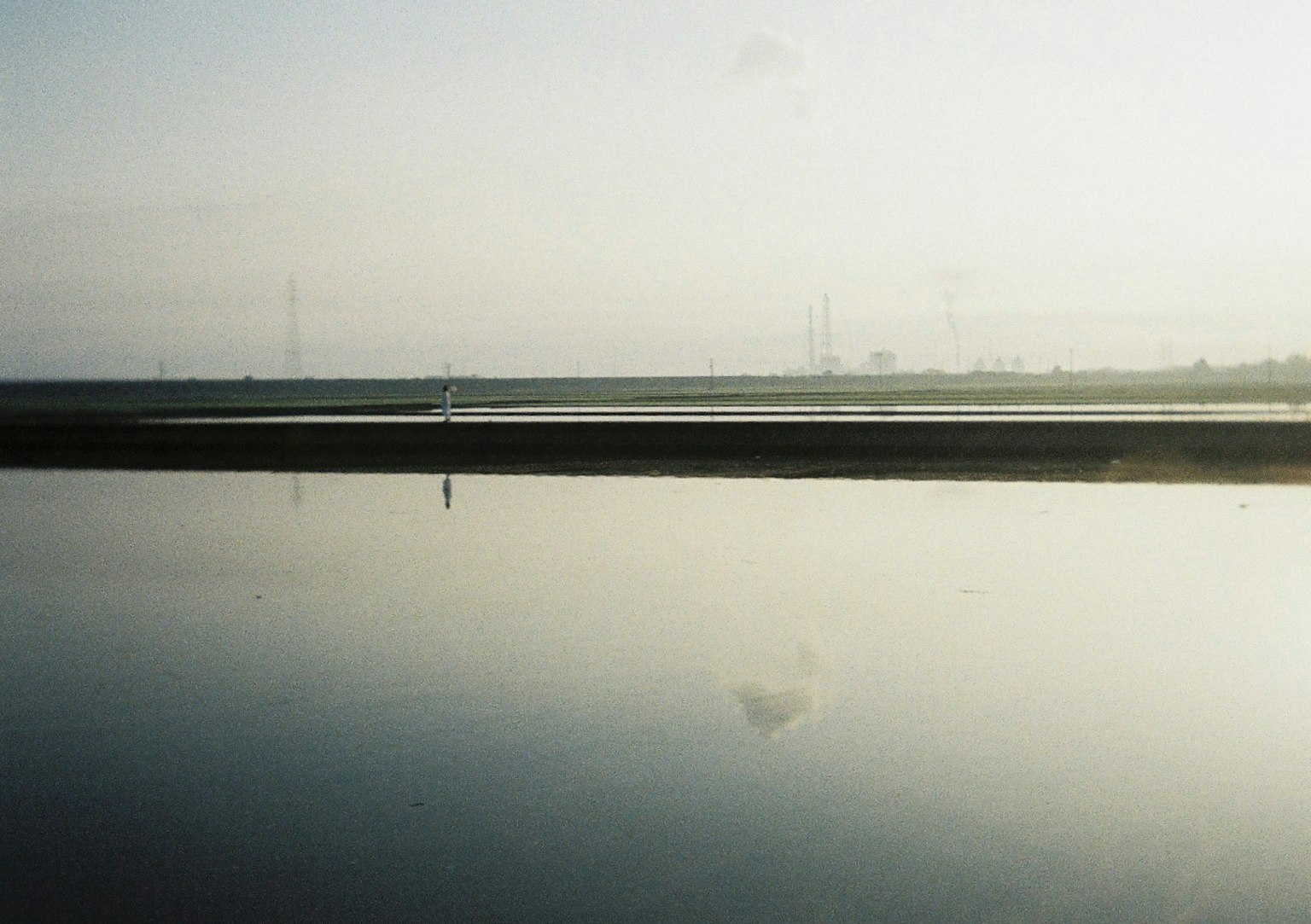 Serene landscape with calm water and distant power lines