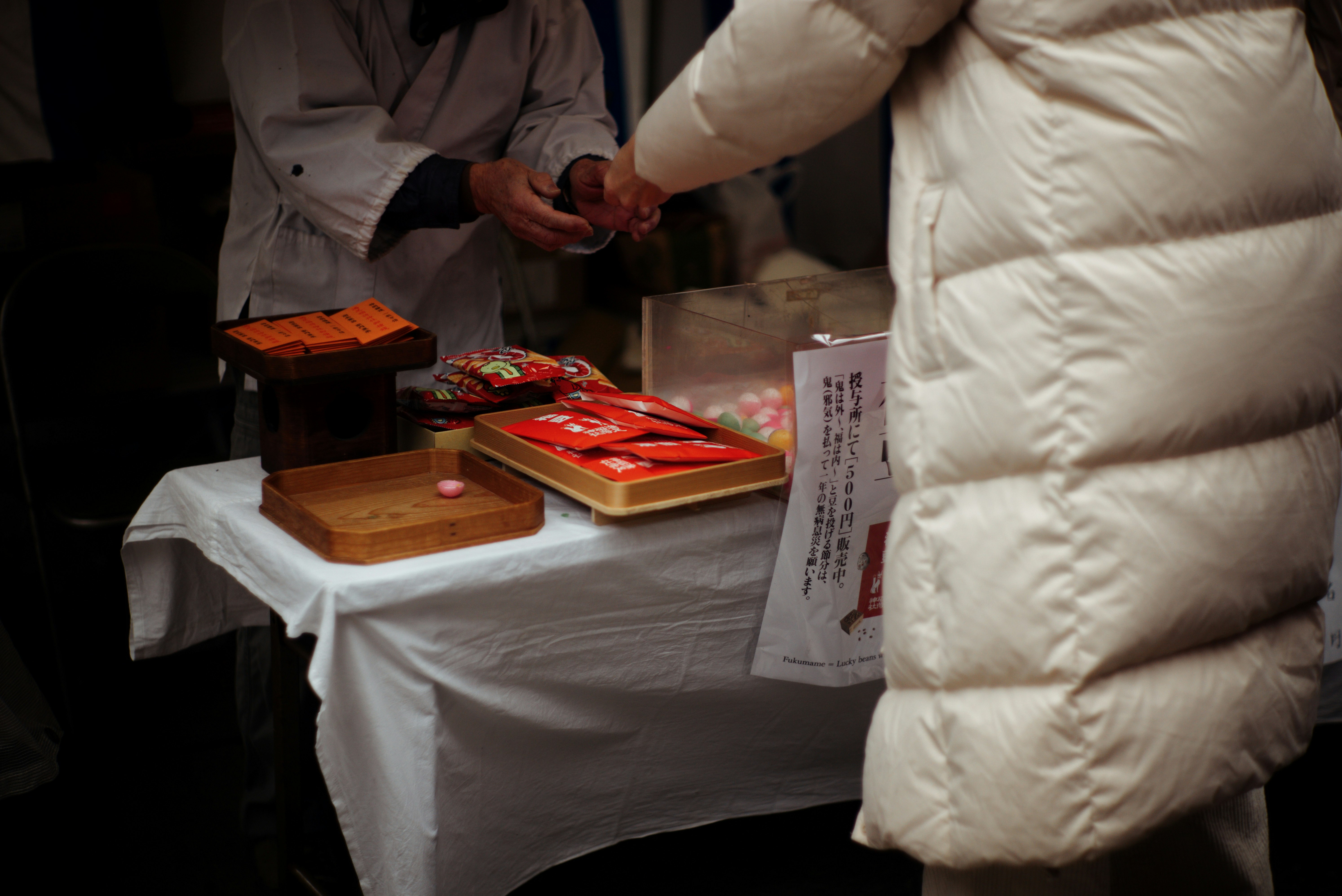白いコートを着た人が屋台で食べ物を受け取っている