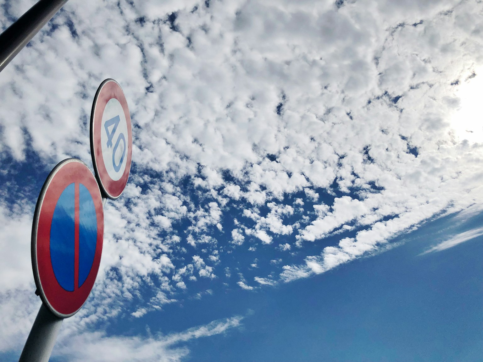 Dua rambu lalu lintas di latar belakang langit biru dan awan