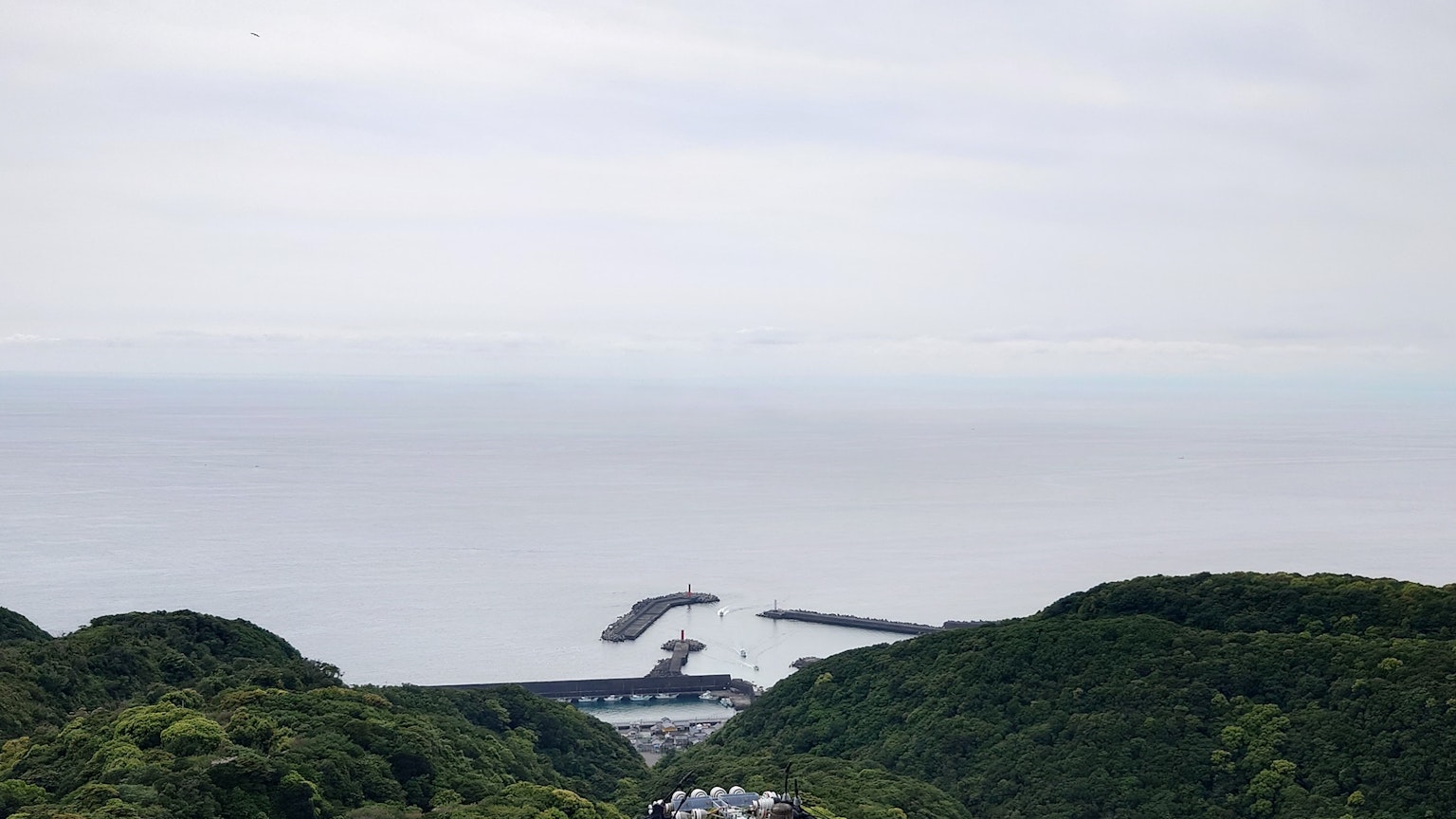 Scenic view of the sea and green hills with visible harbor structures