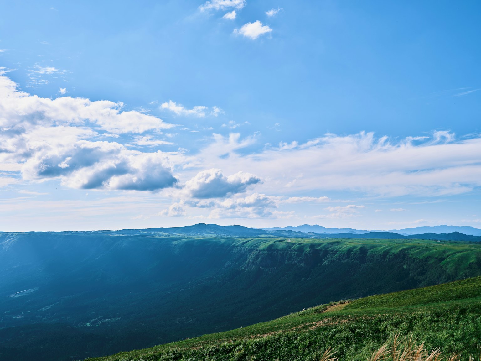 Vista panoramica di montagne verdi sotto un cielo blu con nuvole bianche