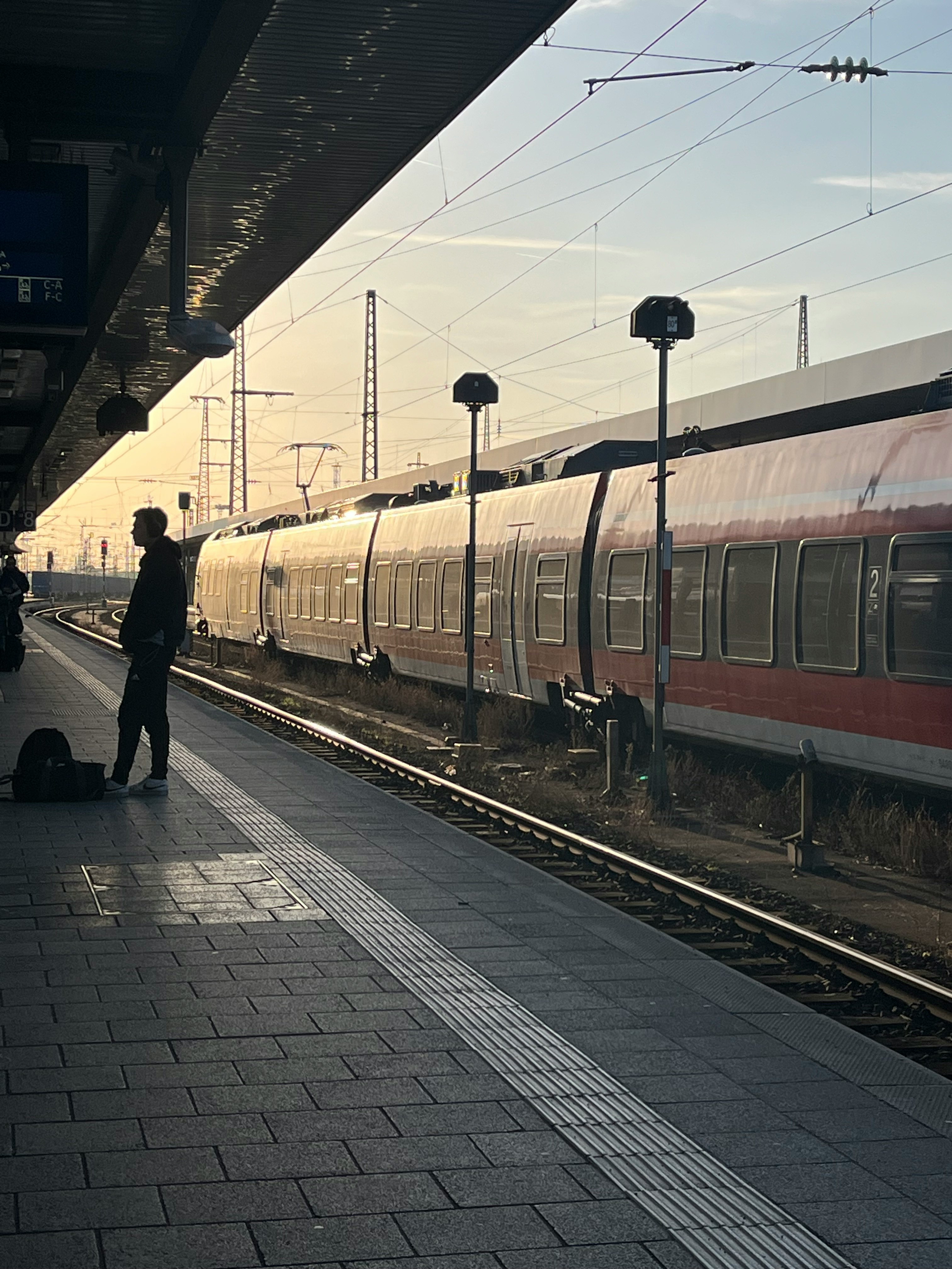 駅のホームで停車する電車と人影