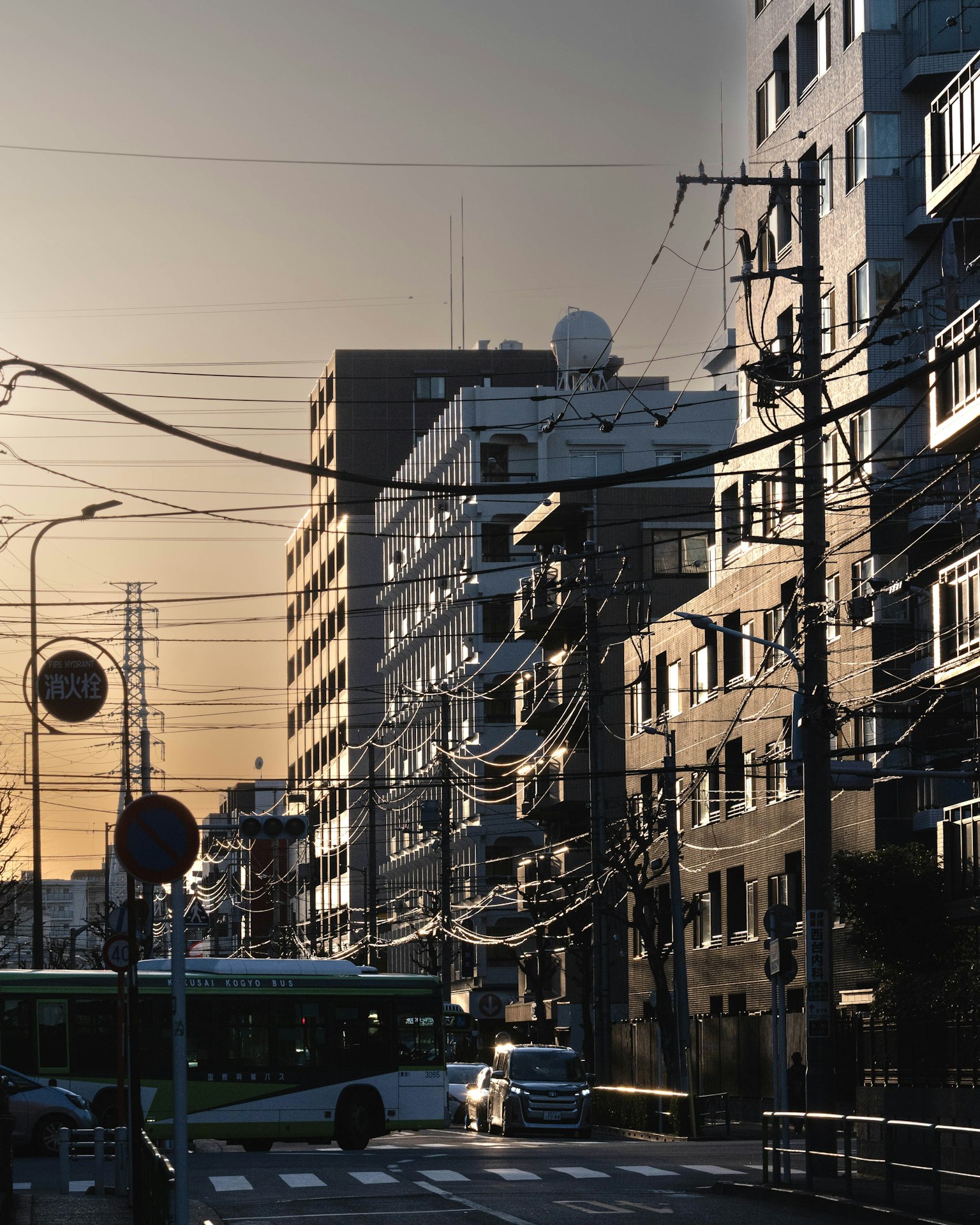 Urban sunset scene featuring high-rise buildings and intersecting power lines with traffic