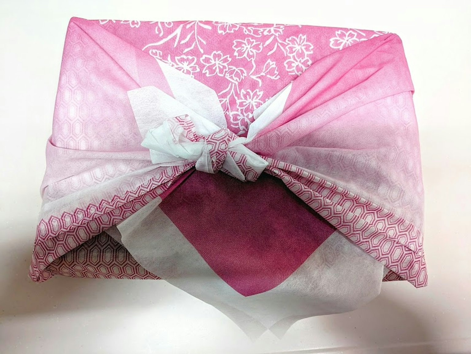 Regalo avvolto in tessuto rosa con motivi floreali
