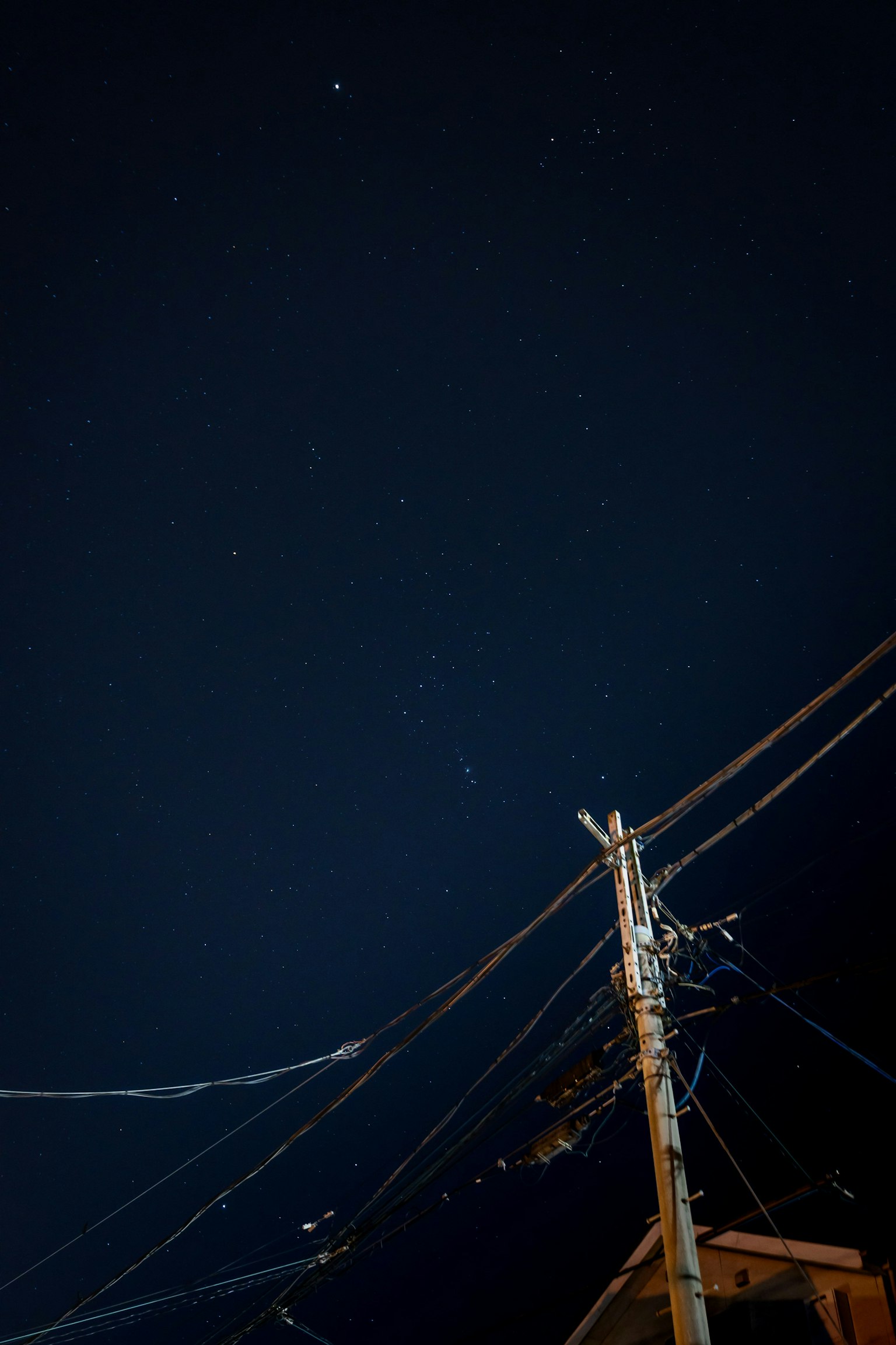 夜空に星が輝く中、電柱と電線が見える風景