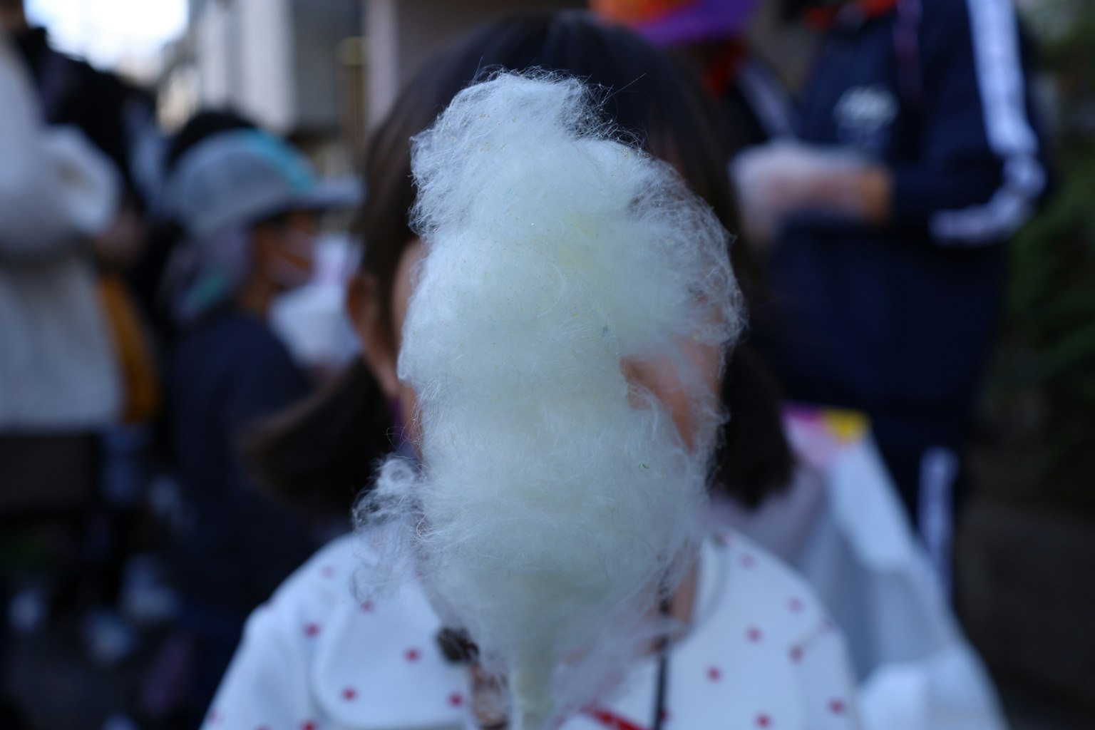 Kind hält Zuckerwatte, die sein Gesicht verdeckt