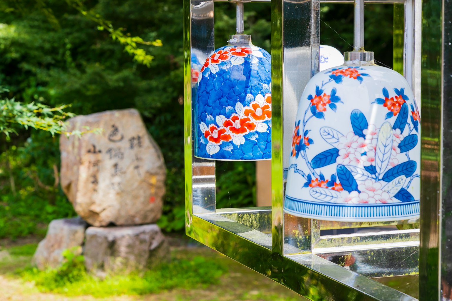 Cloche à vent florale bleue et sculpture en pierre dans un cadre naturel