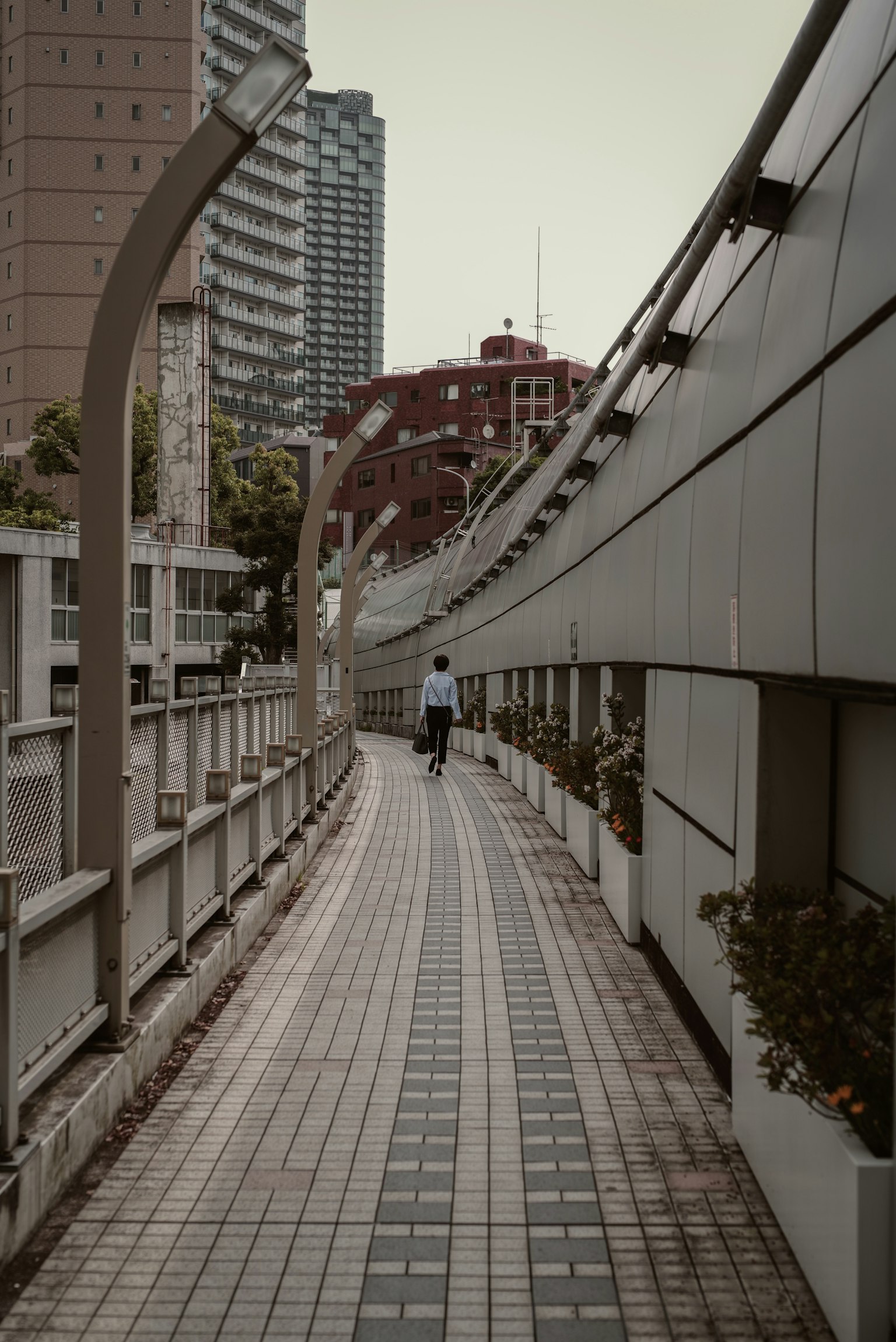 Una persona che cammina su un marciapiede urbano moderno circondato da edifici