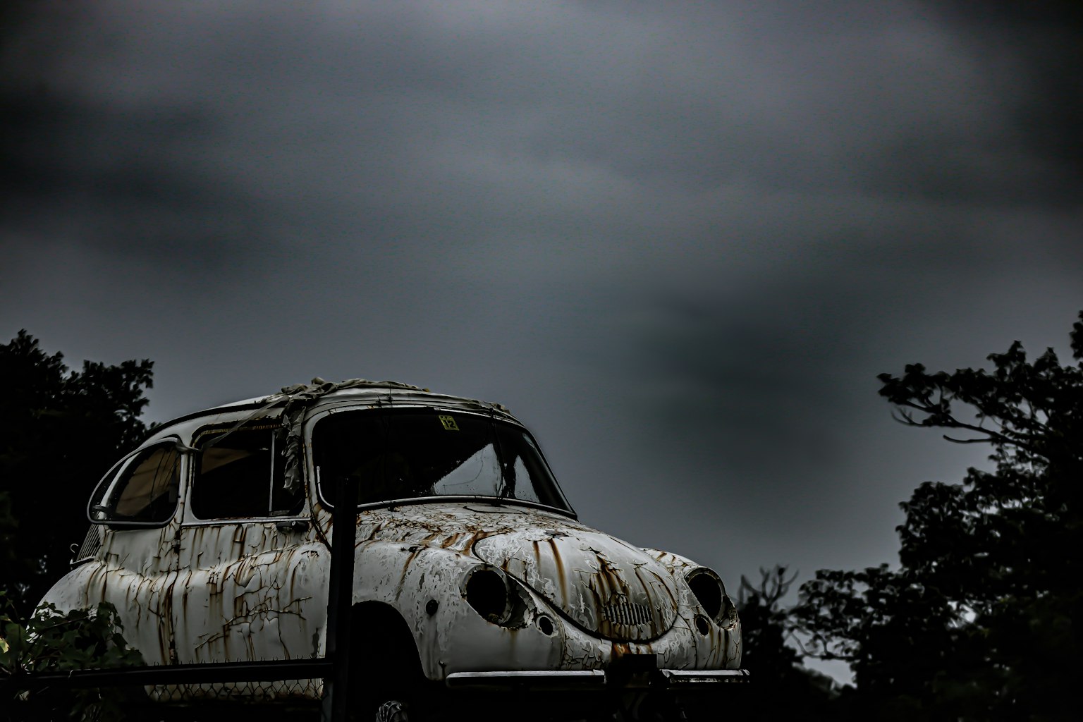 生锈的白色旧车在阴暗的天空下