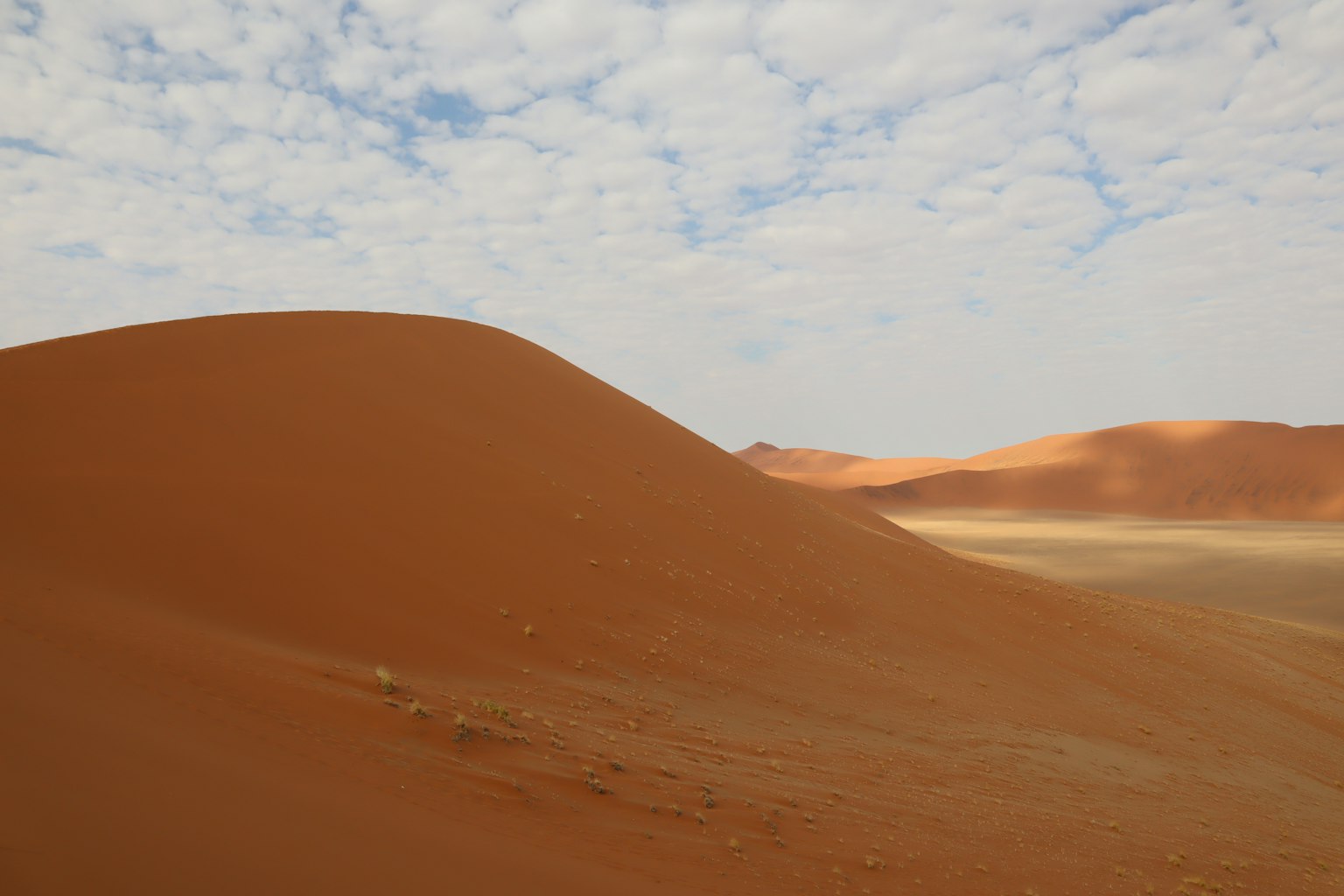 Weite rote Sanddünen unter einem bewölkten Himmel