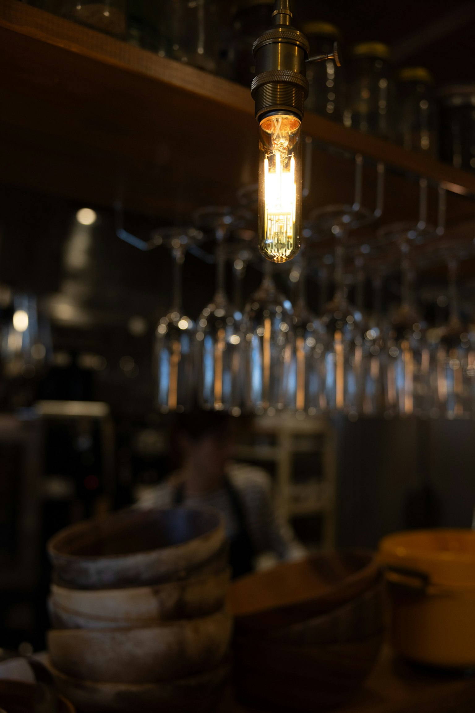 Intérieur d'un bar avec une ampoule vintage suspendue et des rangées de verres