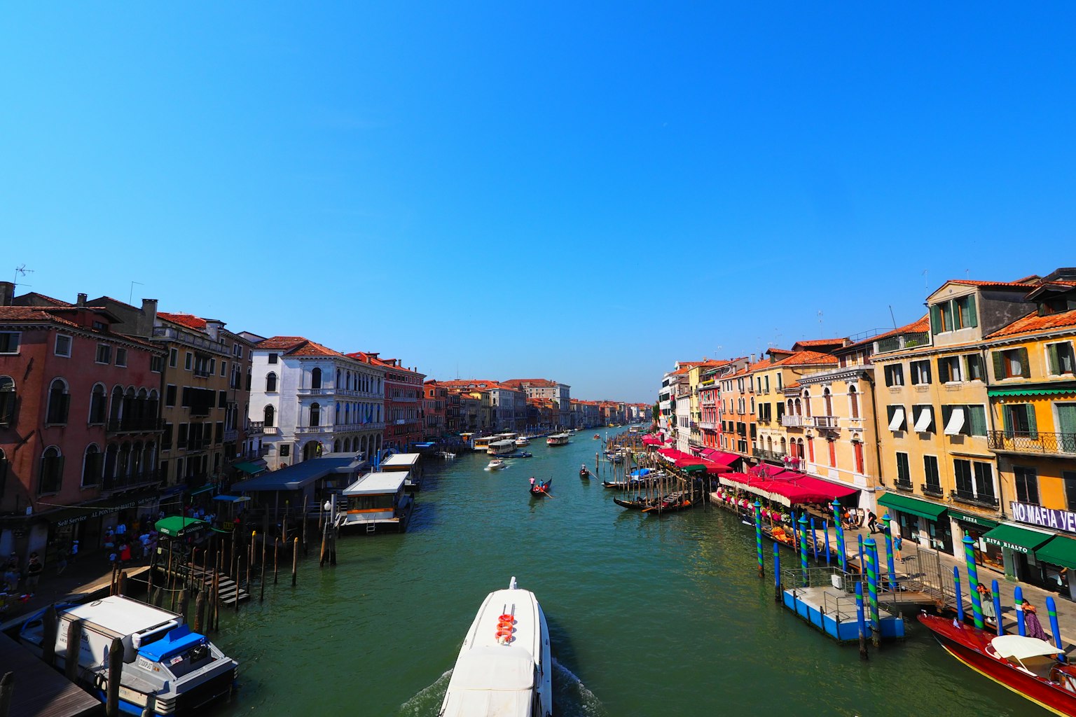 Una vista di un canale veneziano con cielo blu brillante e edifici colorati