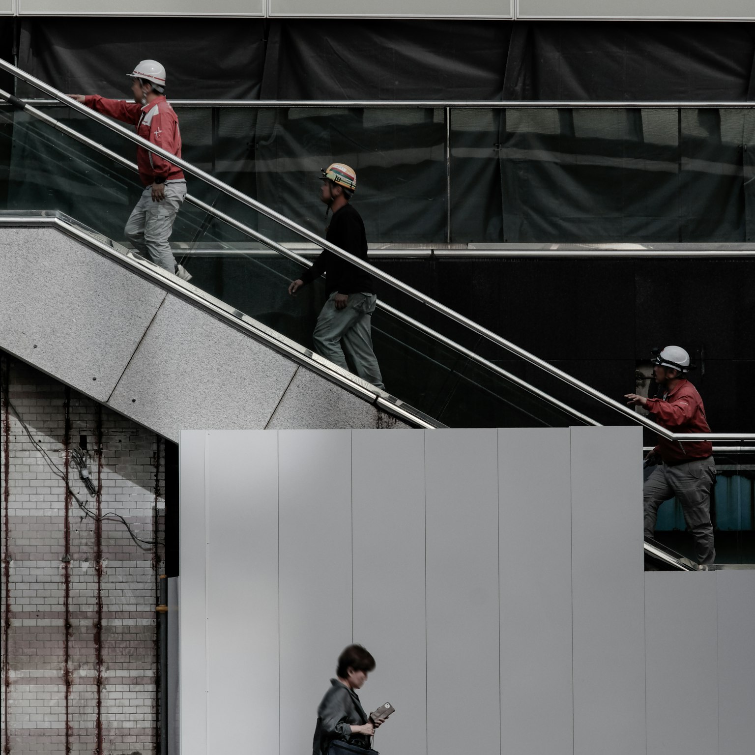 Bauarbeiter, die Treppen steigen, mit einer Frau, die ein Smartphone benutzt