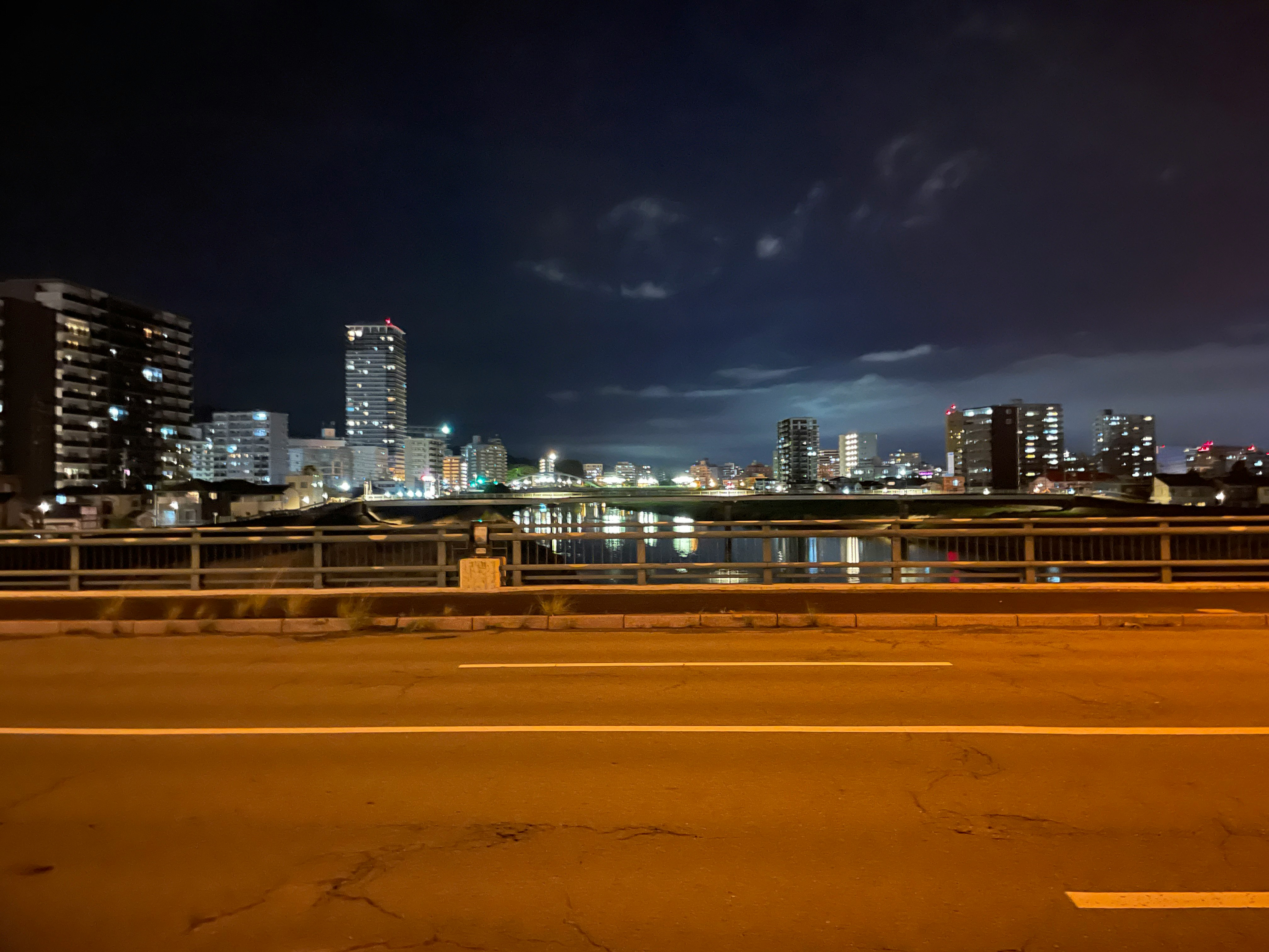 夜の川沿いの遊歩道と街の灯りのスカイライン