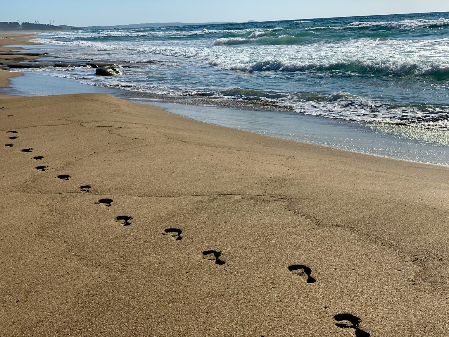 Empreintes sur la plage de sable avec des vagues océaniques
