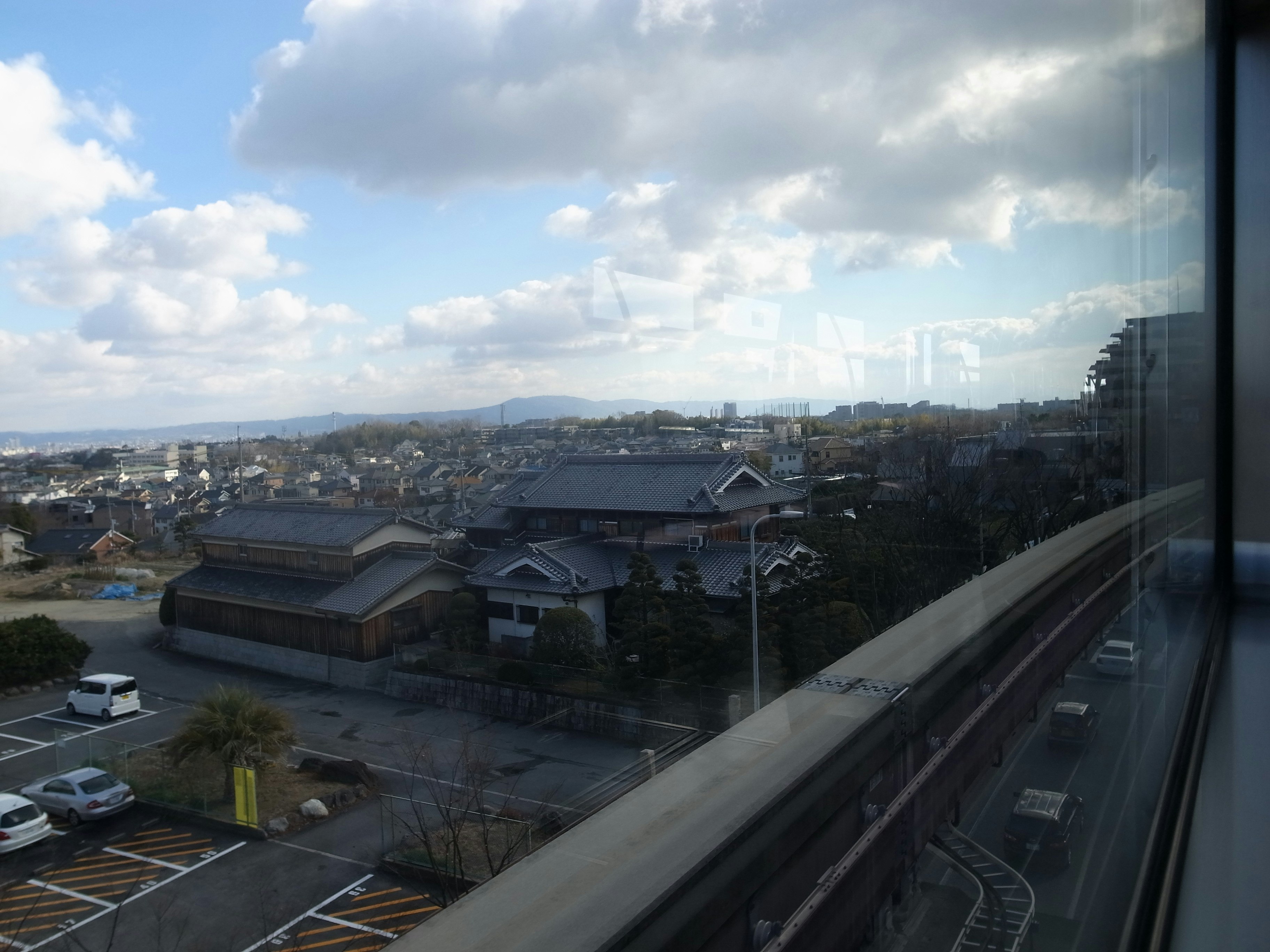 窓越しに見える郊外の住宅街と高速道路
