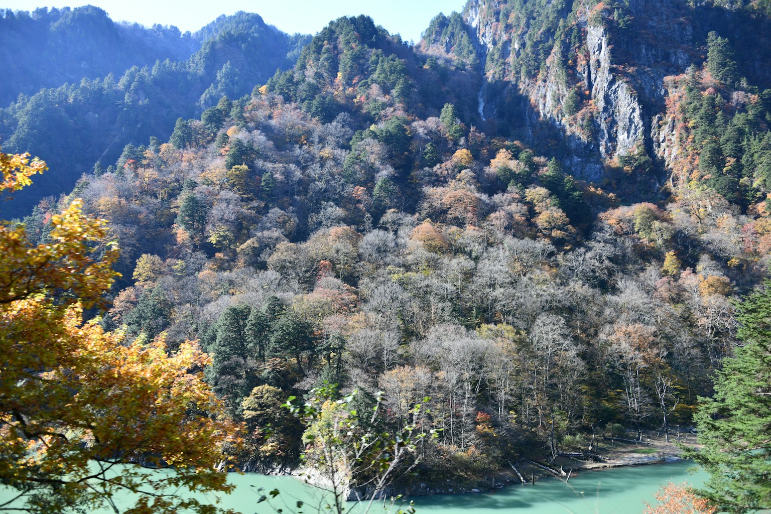 Scenic view of a blue river with autumn foliage on mountains