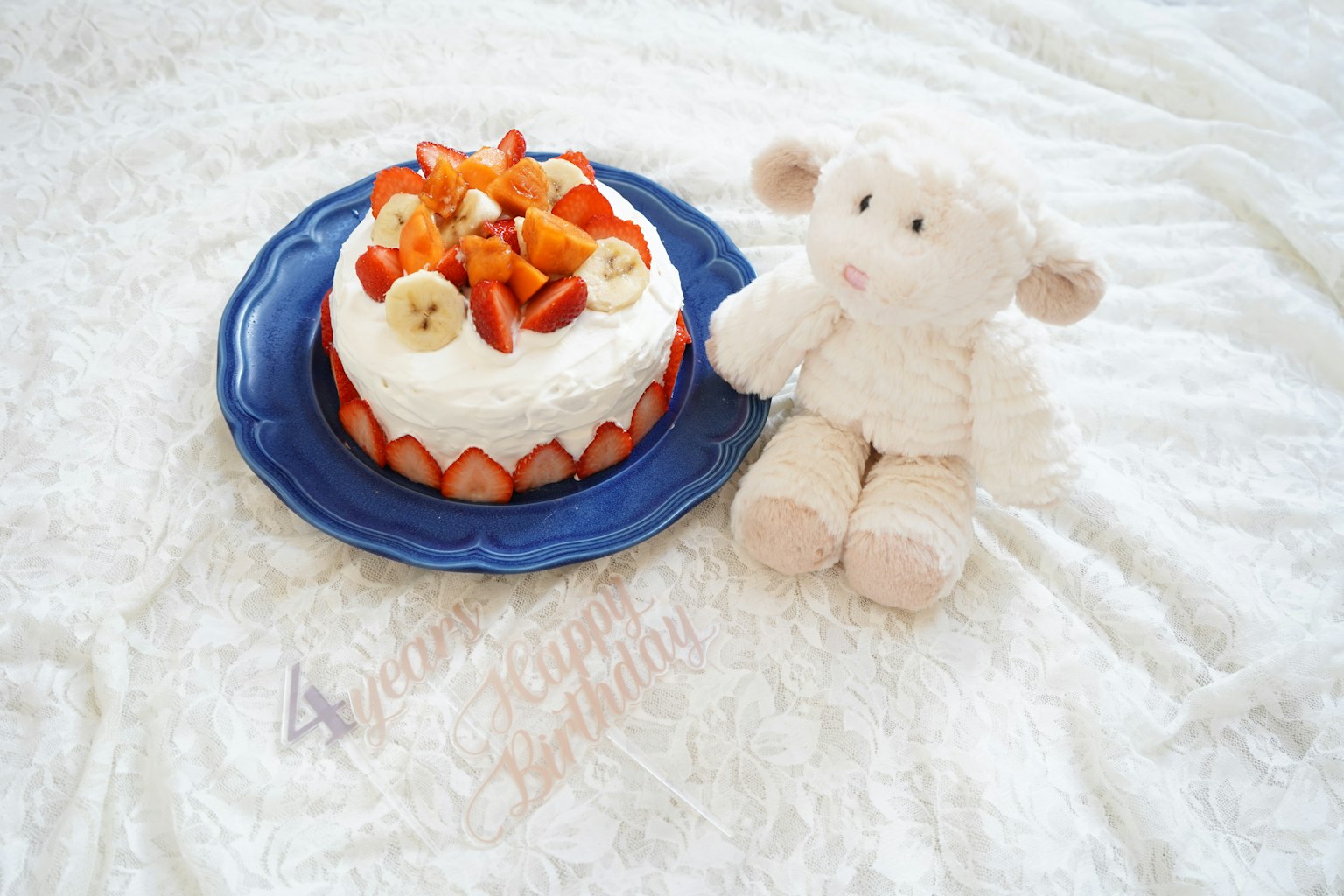 Jouet en peluche de mouton blanc à côté d'un gâteau à la crème garni de fraises