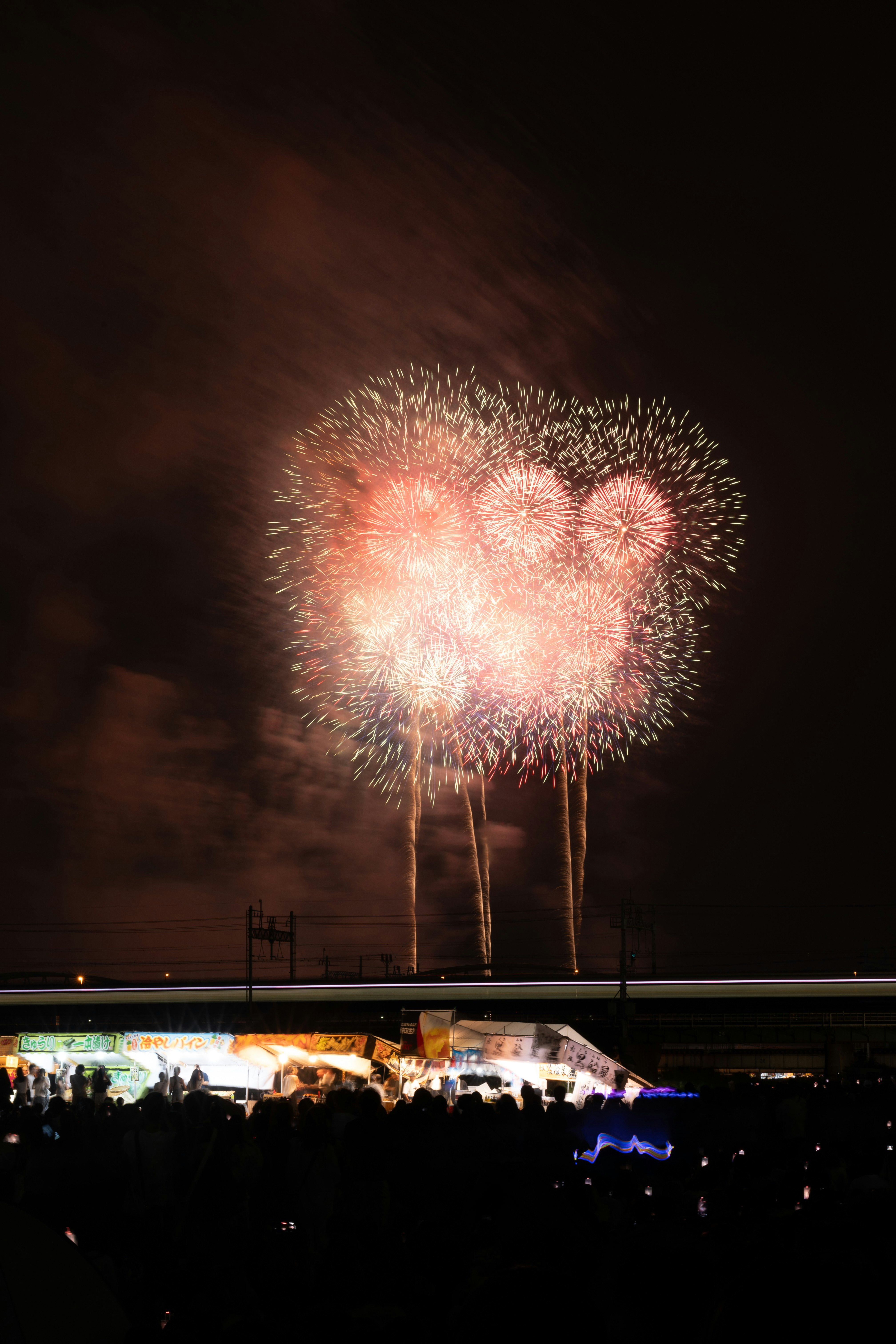 夜空に咲く花火と屋台のある広場の風景