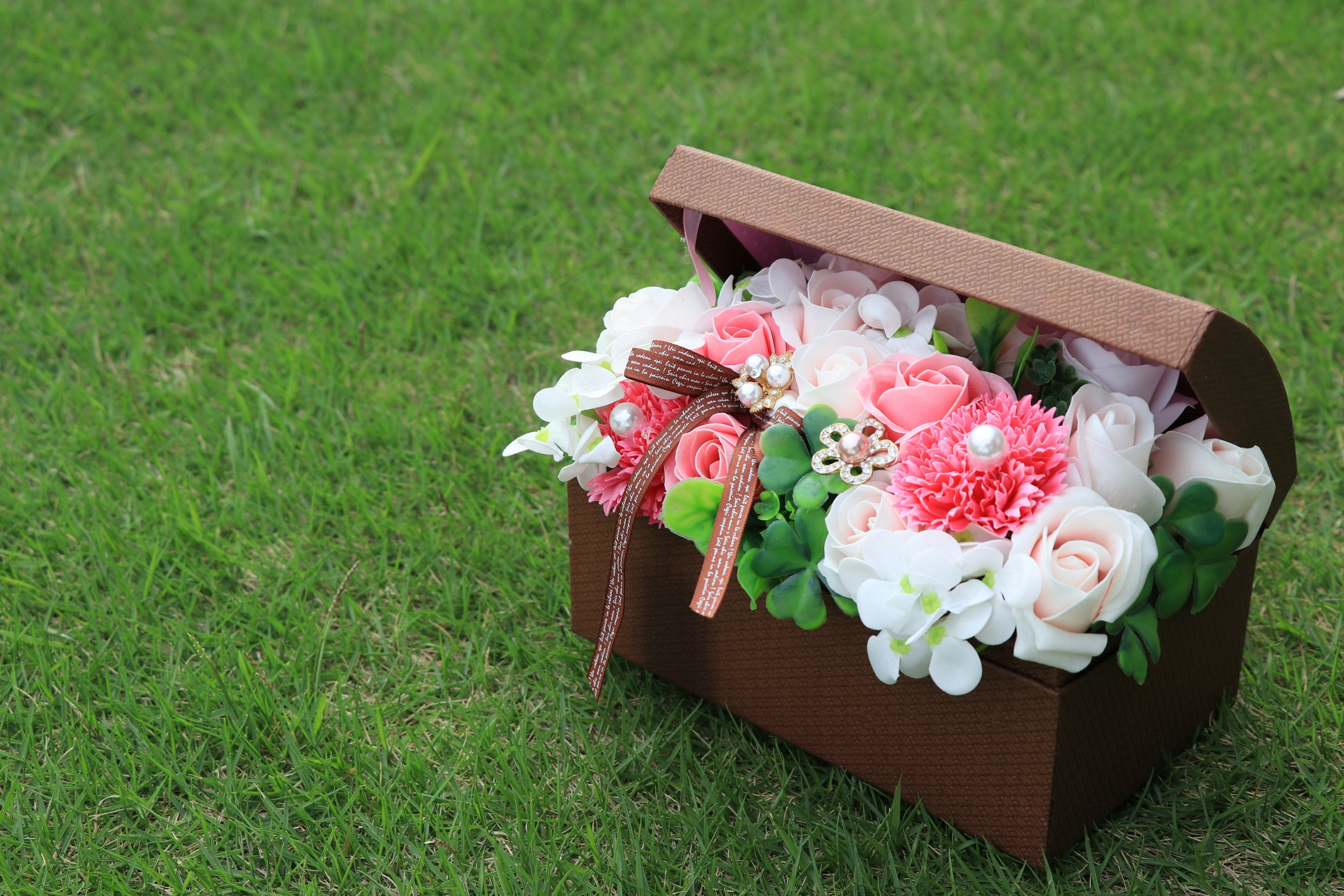 kotak hadiah berisi buket bunga di atas rumput