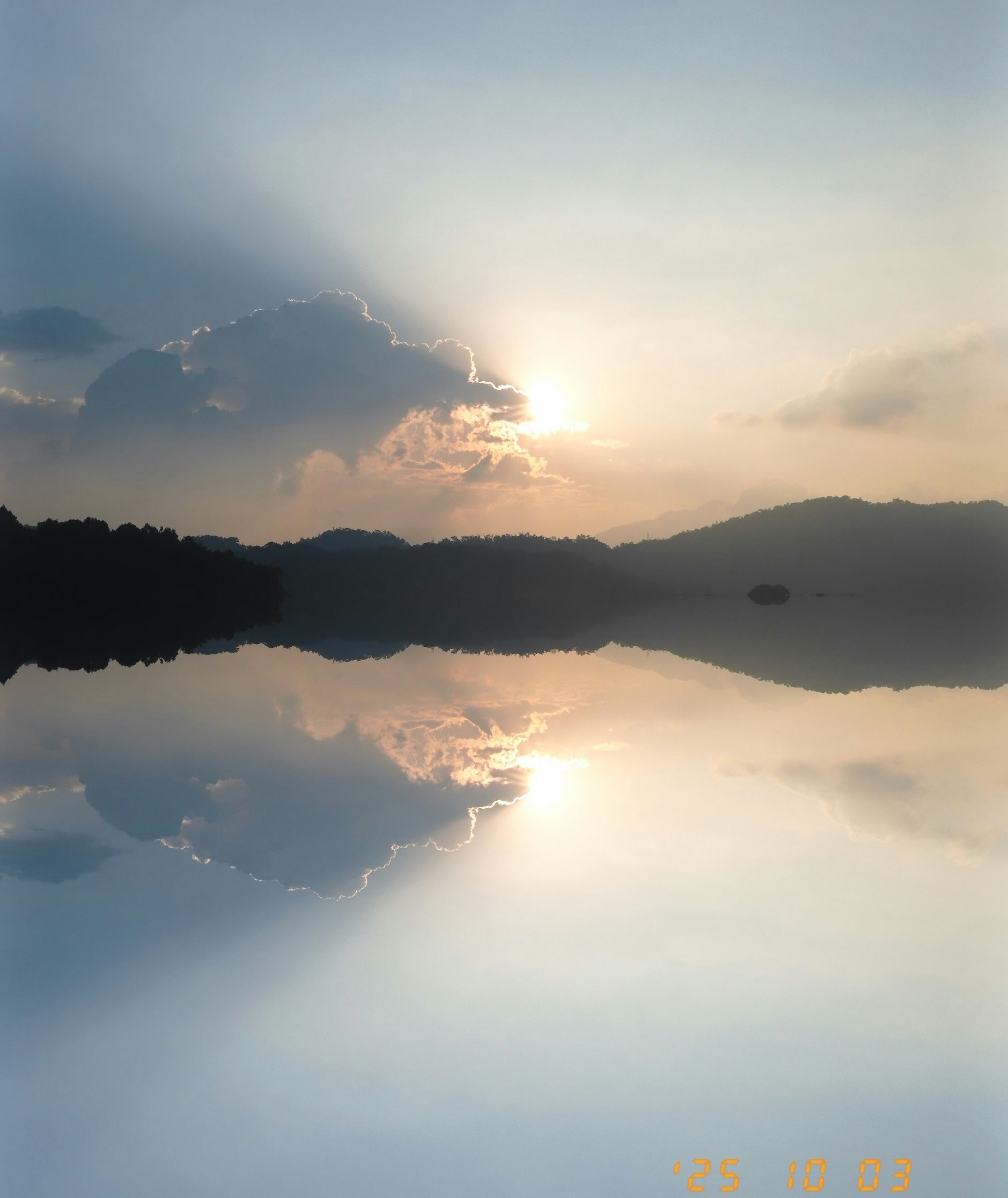 湖面に映る夕日と雲のある山並みの風景