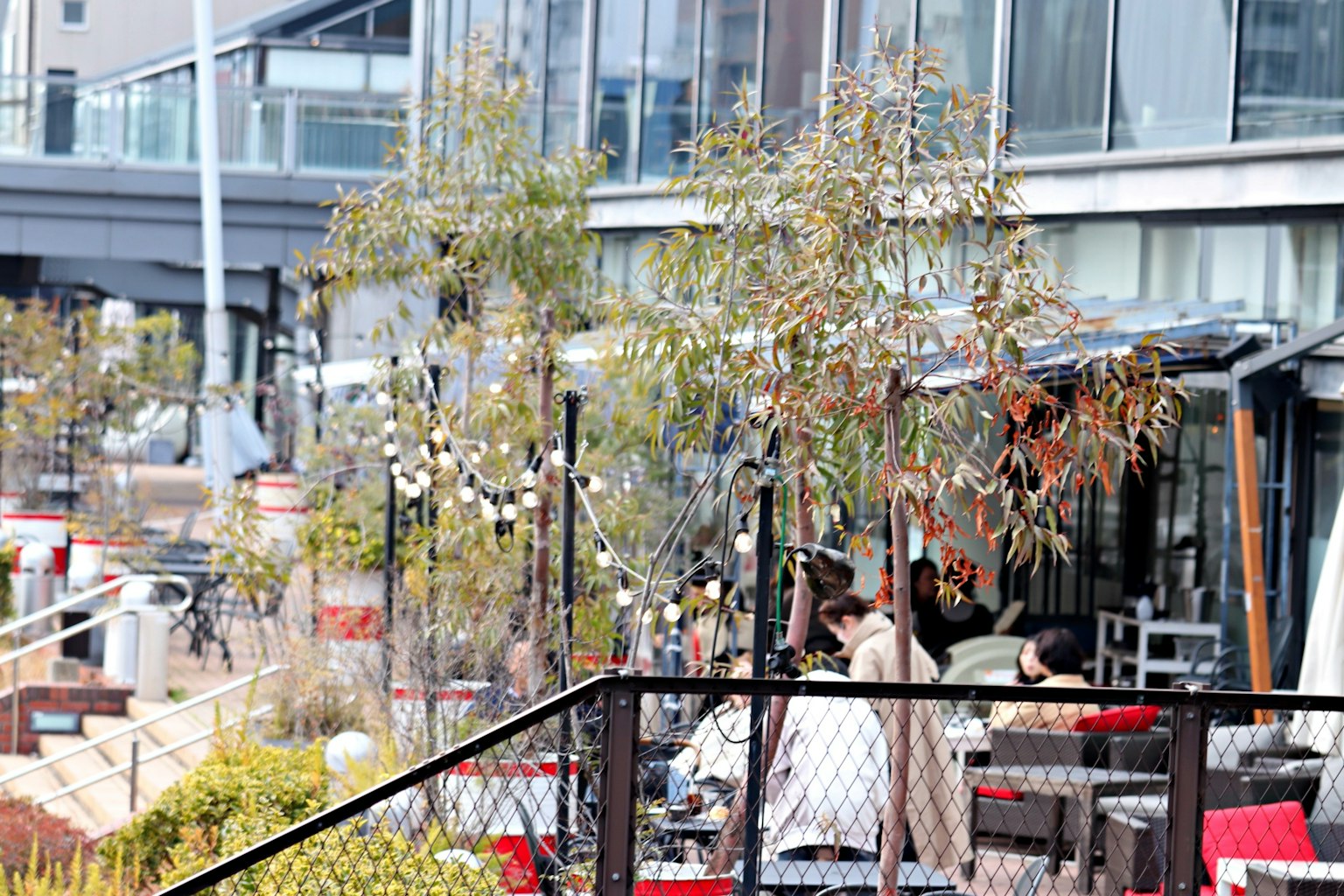 Menschen sitzen auf einer Caféterrasse umgeben von Pflanzen