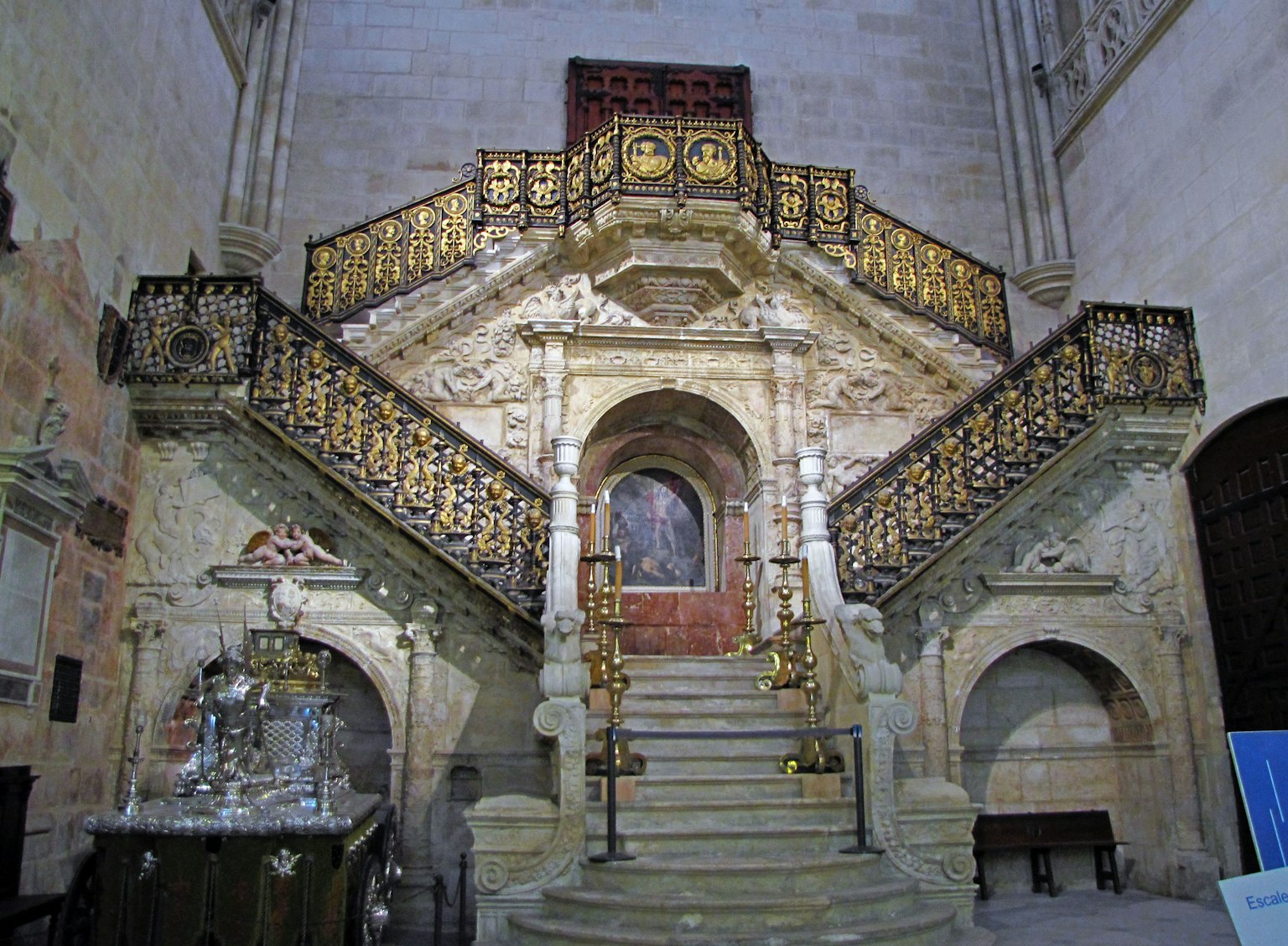 Innenraum einer Kirche mit einer kunstvollen Treppe und goldenen Geländern