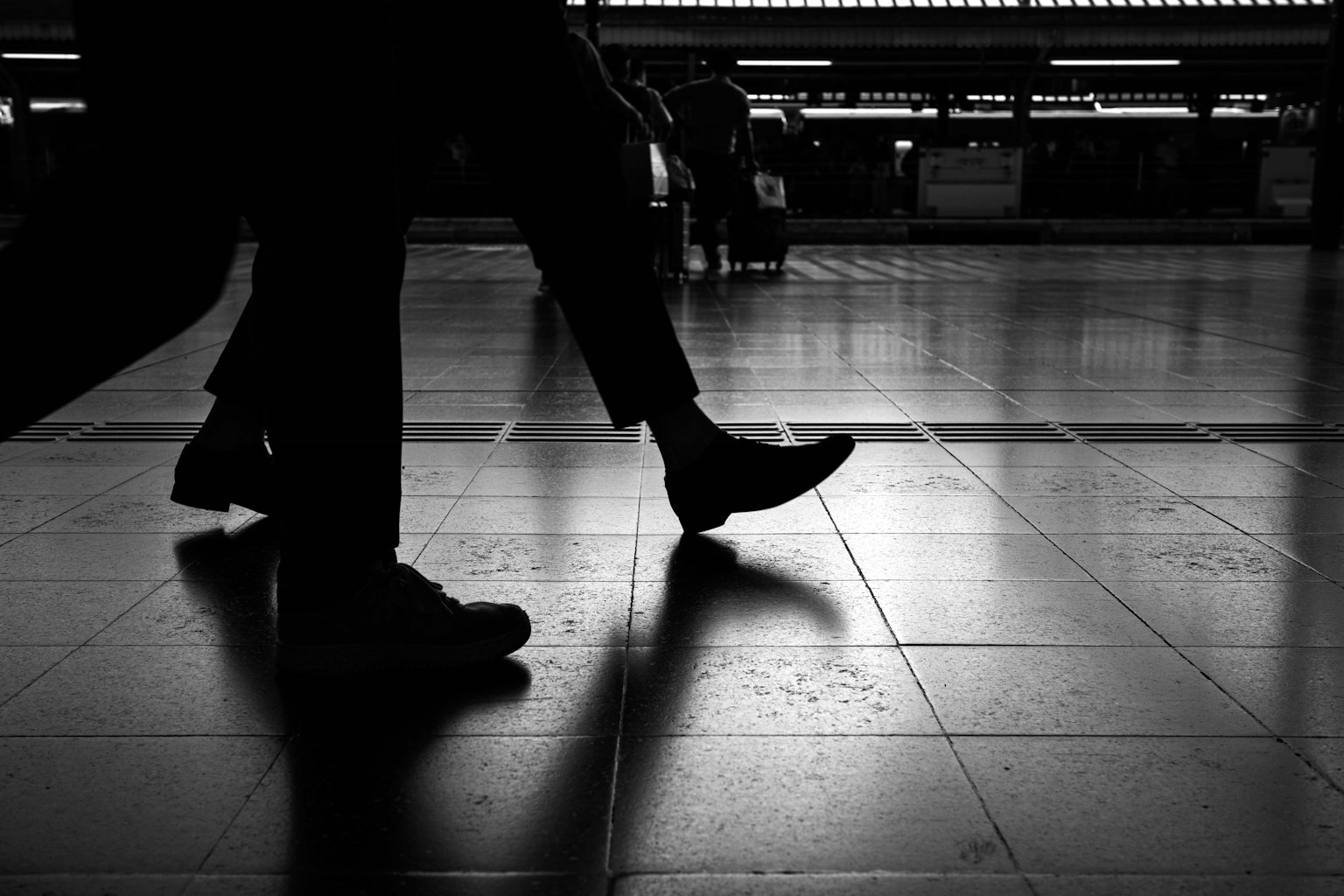 Des personnes marchant dans une station avec un contraste de lumière et d'ombre