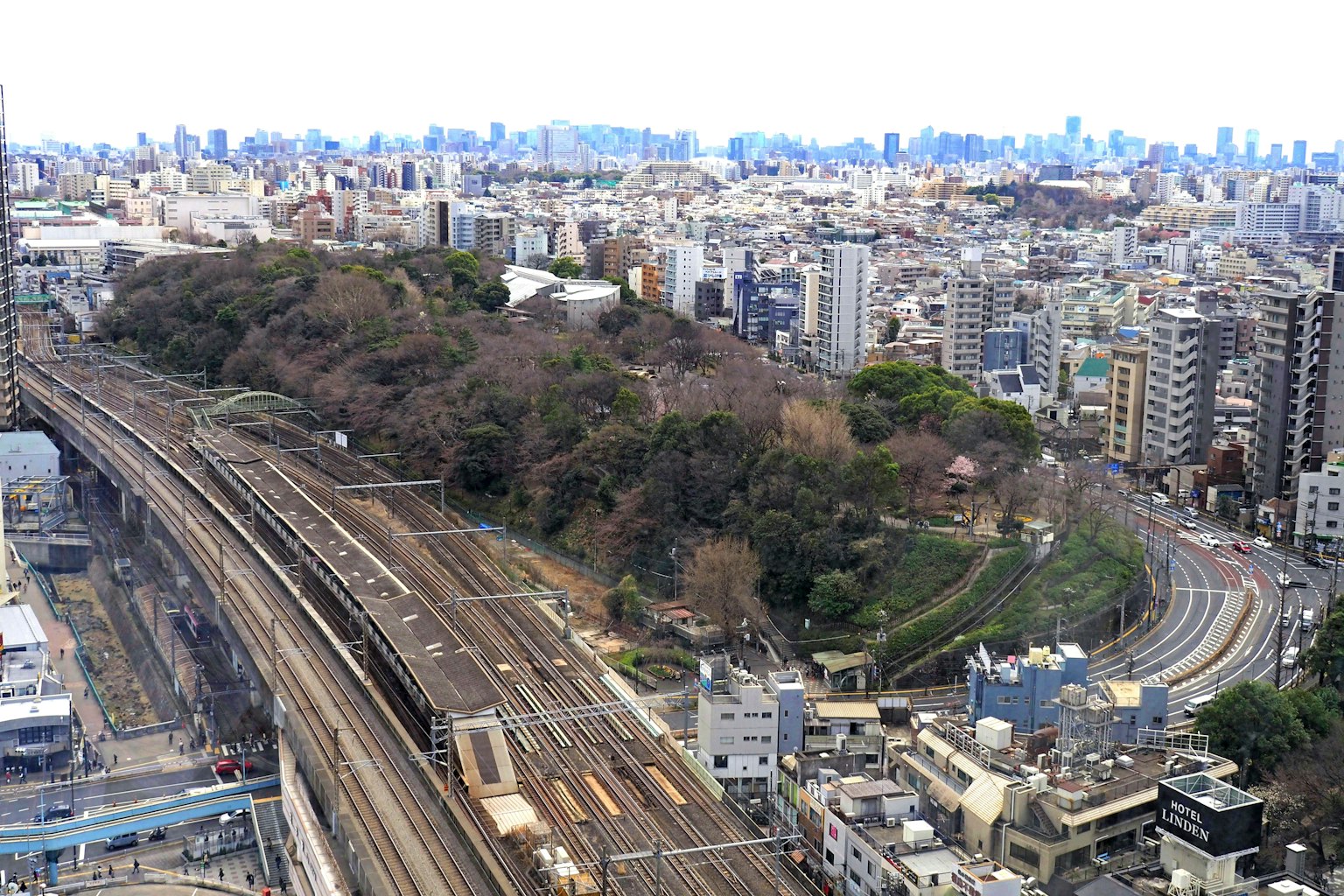Vista aérea de un paisaje urbano con vías de tren y colinas verdes