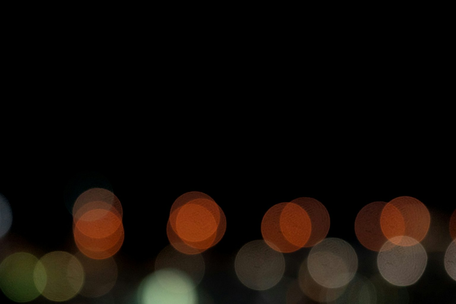 Escena nocturna borrosa con luces bokeh coloridas sobre un fondo negro