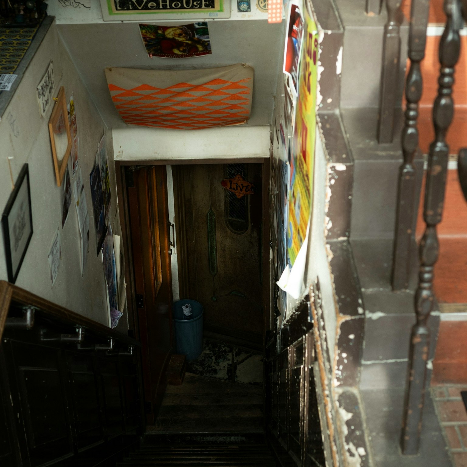 Image d'une vue depuis le haut d'un escalier avec des affiches sur les murs escaliers en bois menant à une porte