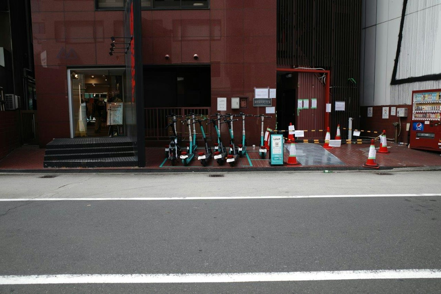 E-Scooter vor einem roten Gebäude mit Verkehrshütchen aufgereiht