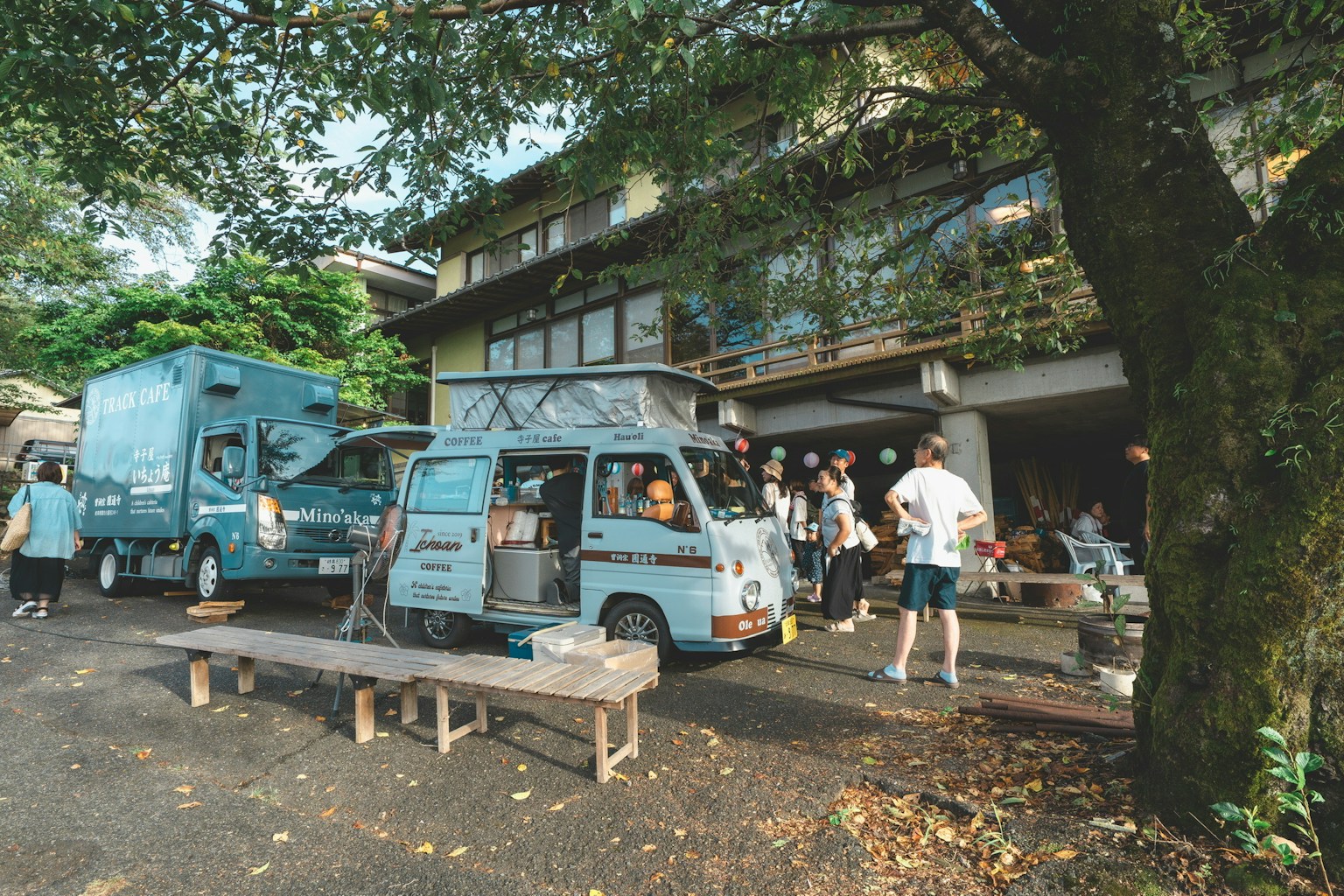 A lively outdoor scene with blue food trucks and people gathering