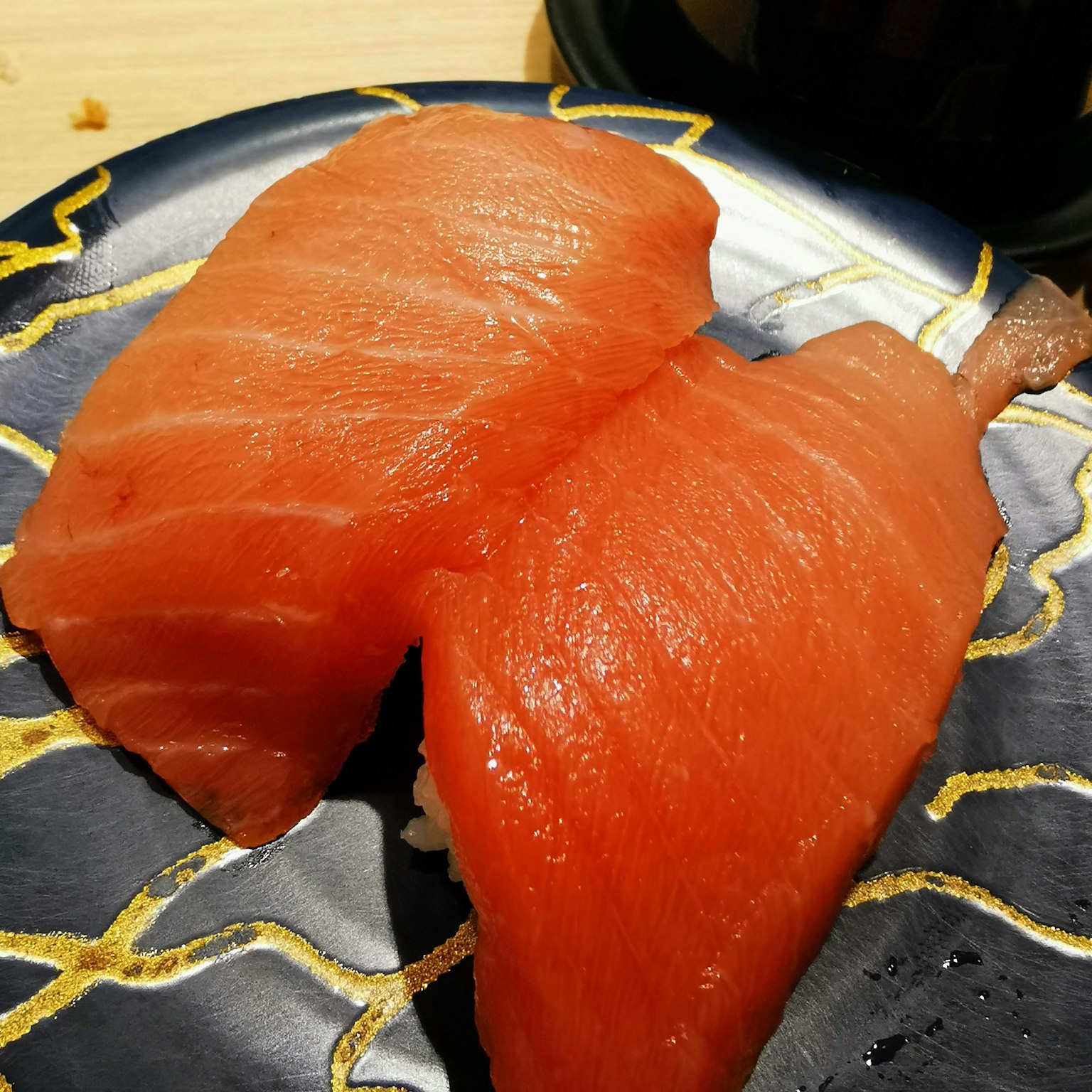 ซูชิเนกิริแซลมอนสีส้มสดใสวางอยู่บนจานสีดำ