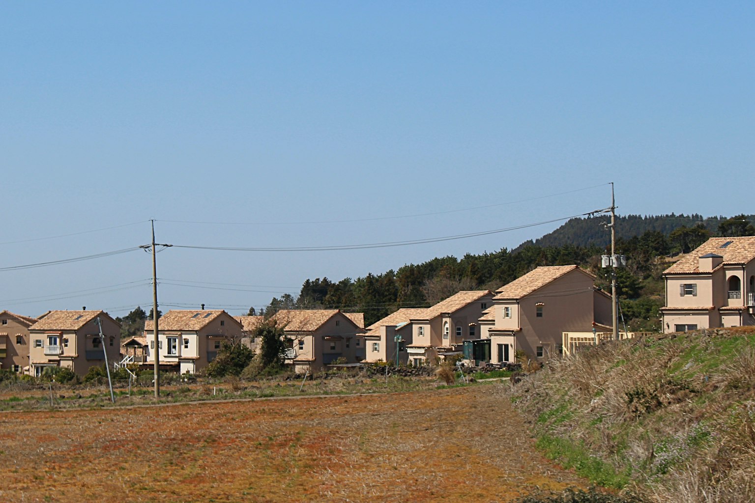 Case allineate sotto un cielo blu con campi