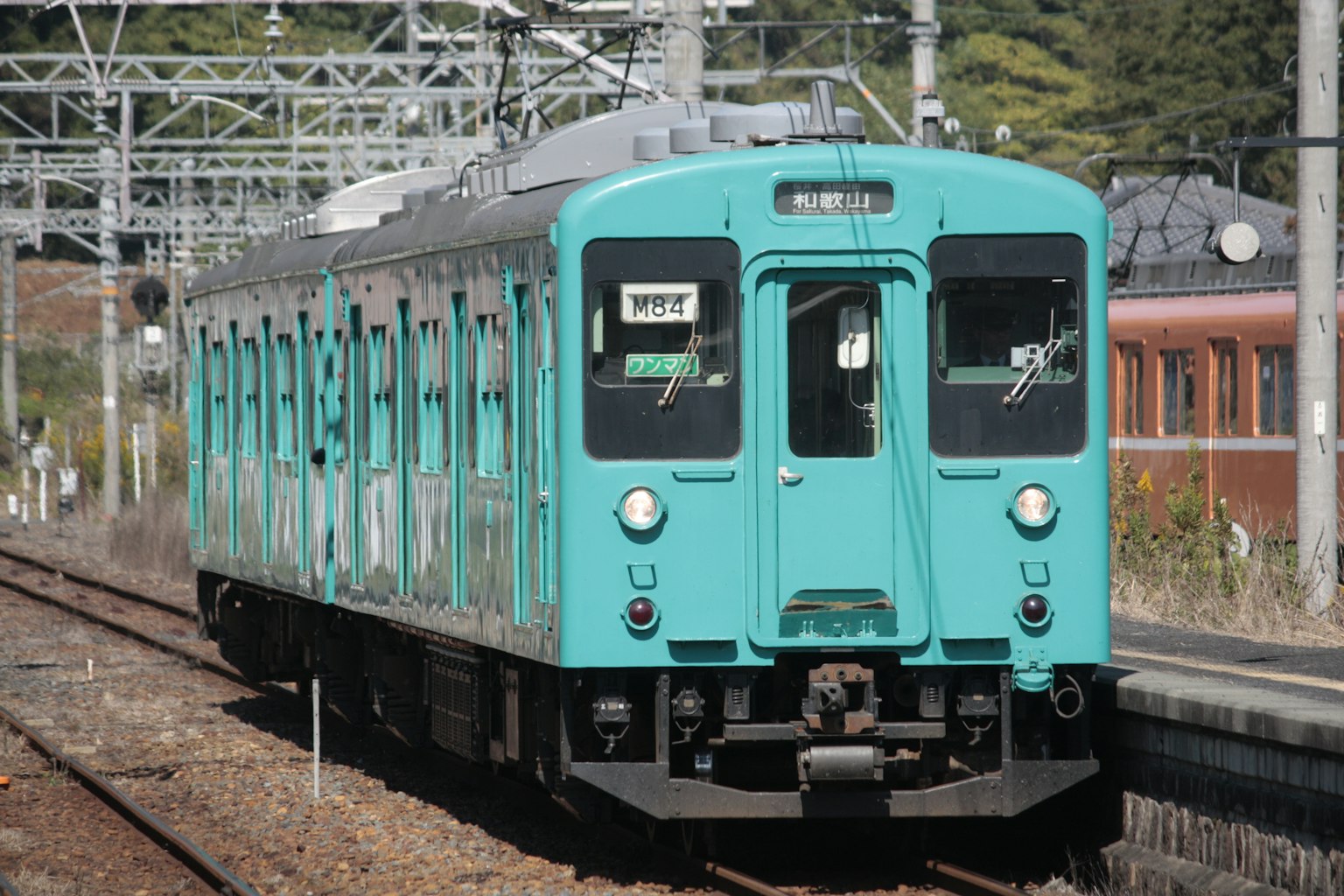 Un tren azul verdoso detenido en una estación