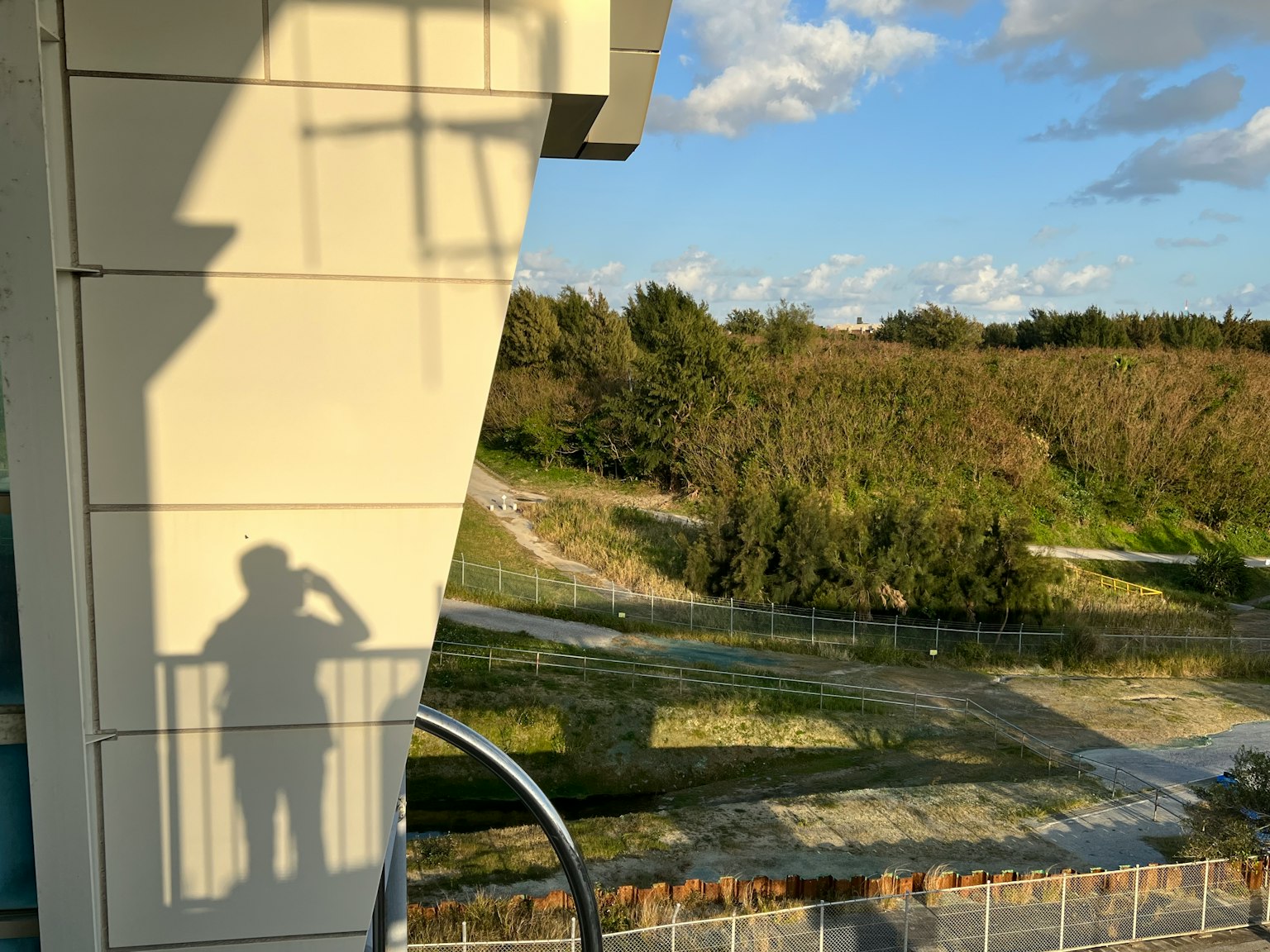 Silueta de una persona de pie contra la sombra de un edificio con cielo azul