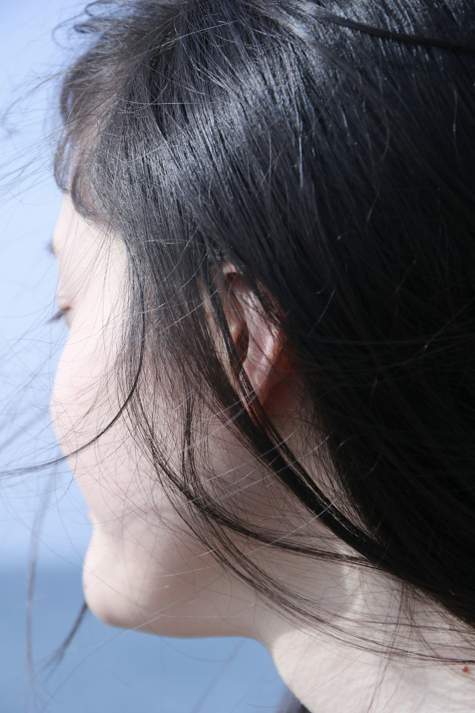 Profile of a woman with long hair against a blue sea background