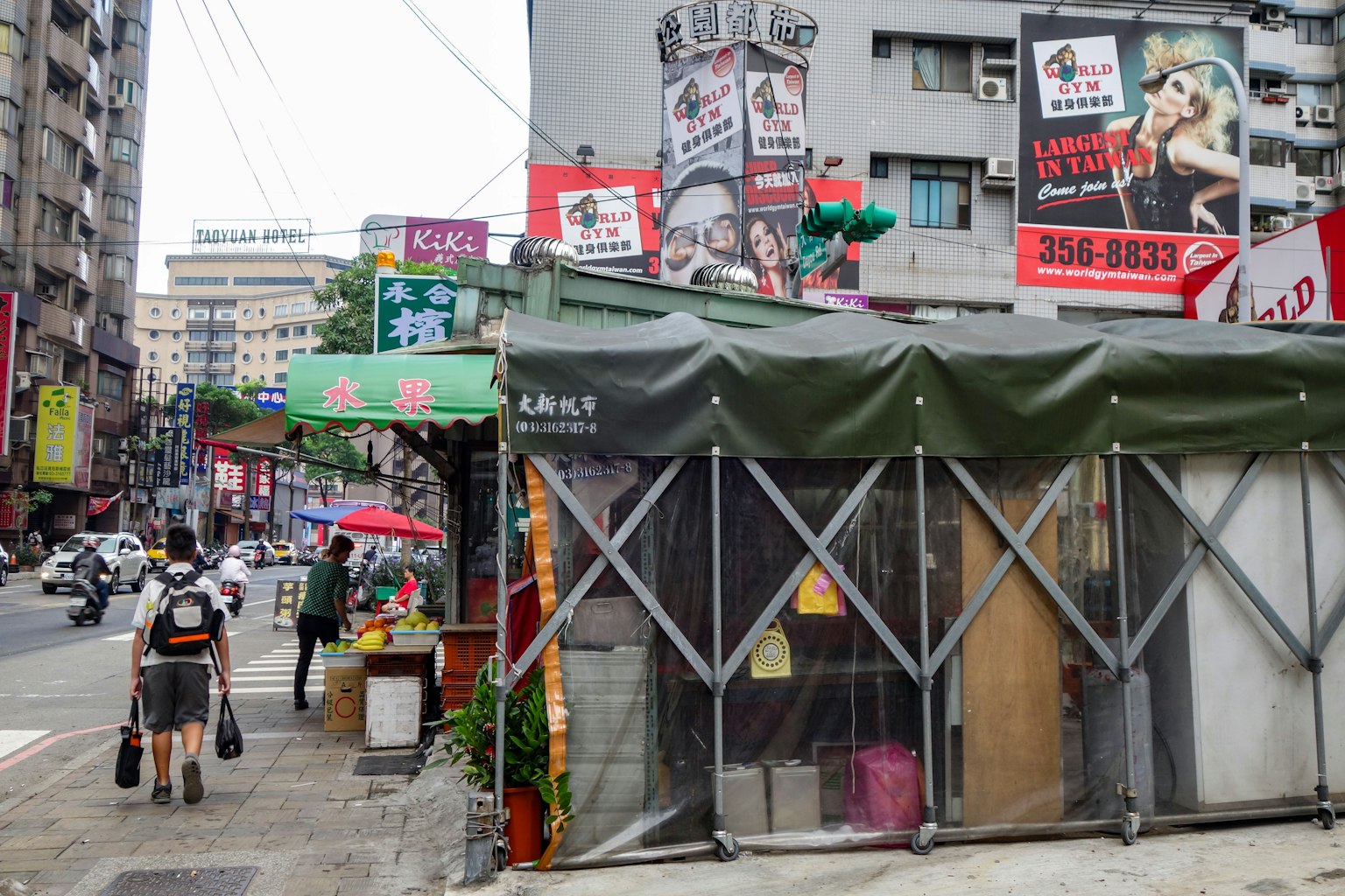 一个繁忙的街角场景，特色是绿色帐篷和各种商店的广告