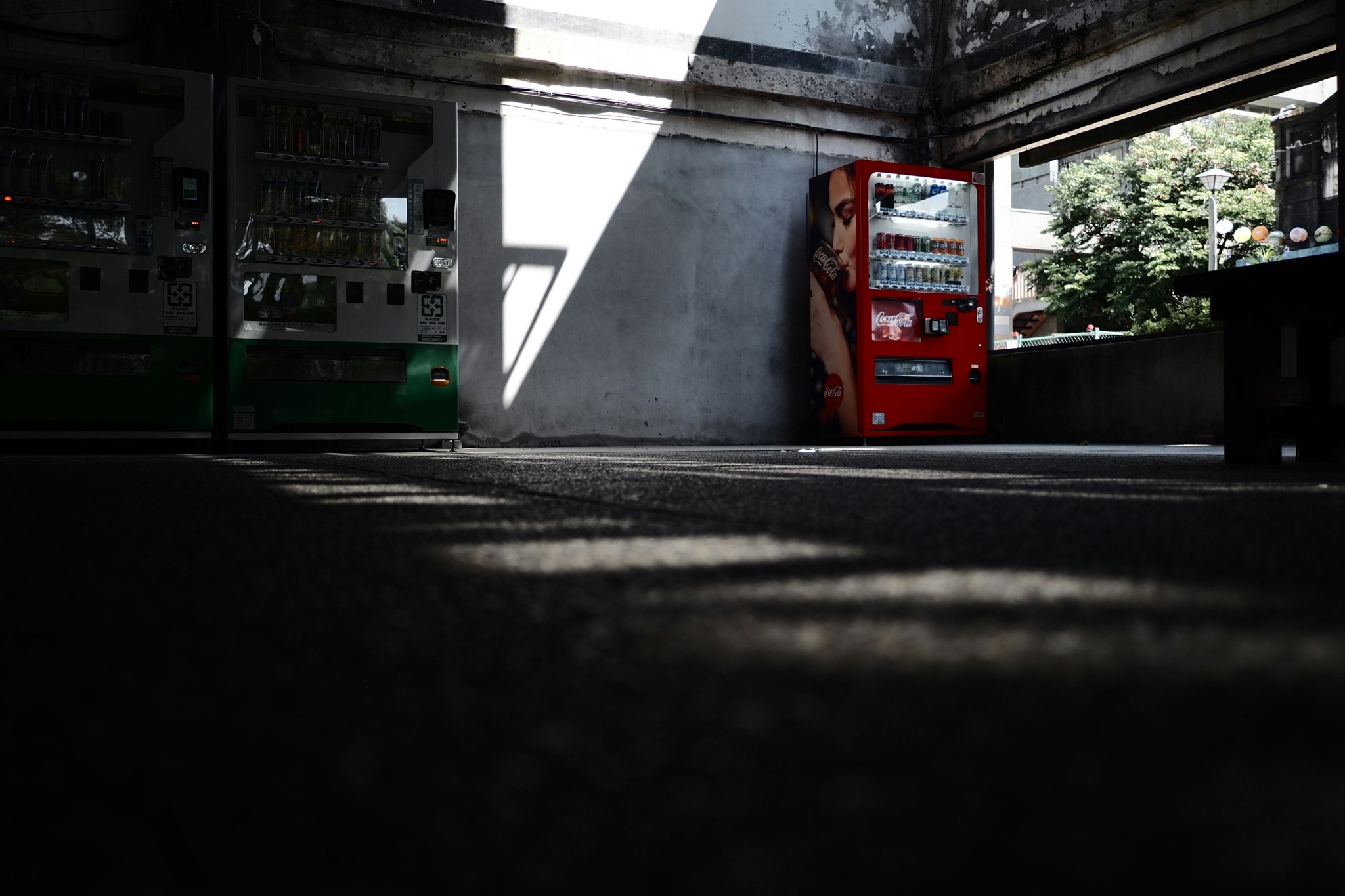 高架下の薄暗い路地に停まる赤い電話ボックス