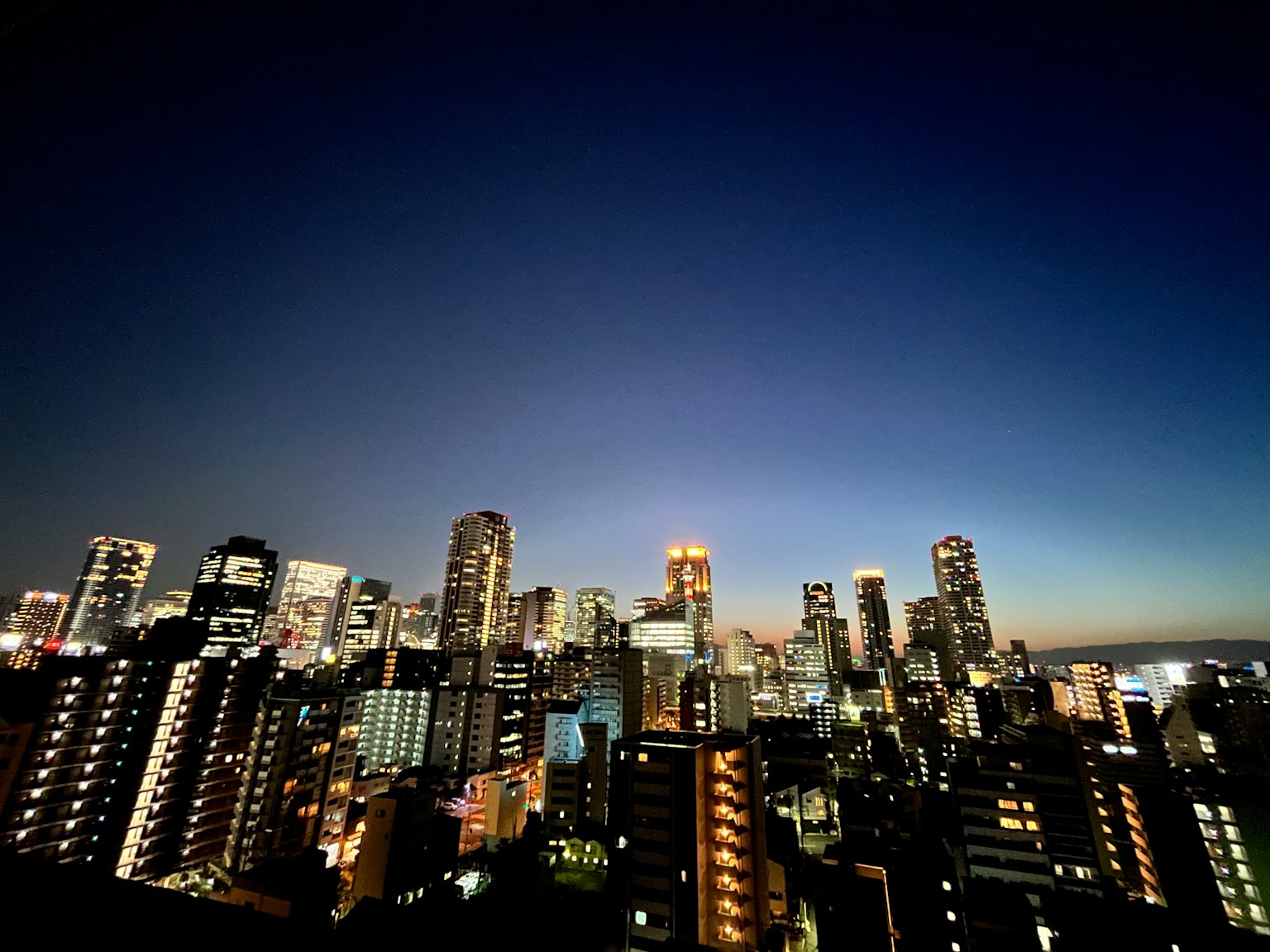 Garis langit kota di malam hari dengan gedung pencakar langit yang menerangi