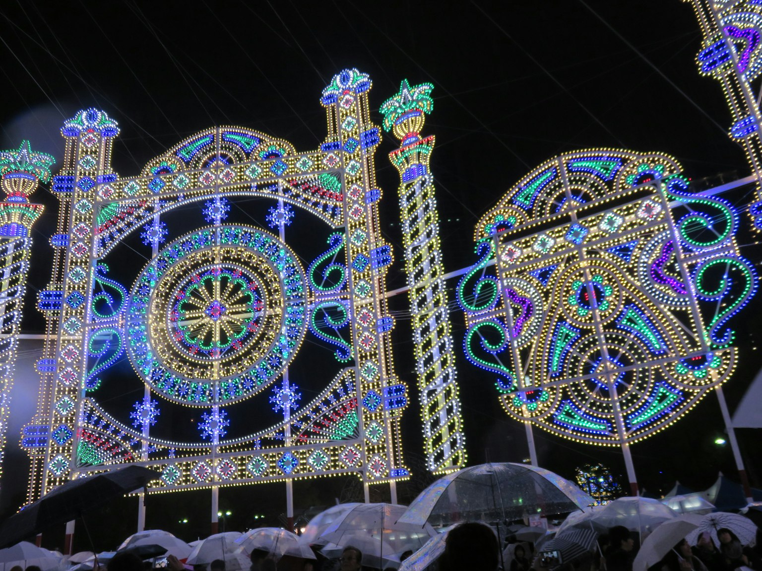 Decoraciones iluminadas coloridas con diseños intrincados y personas con paraguas
