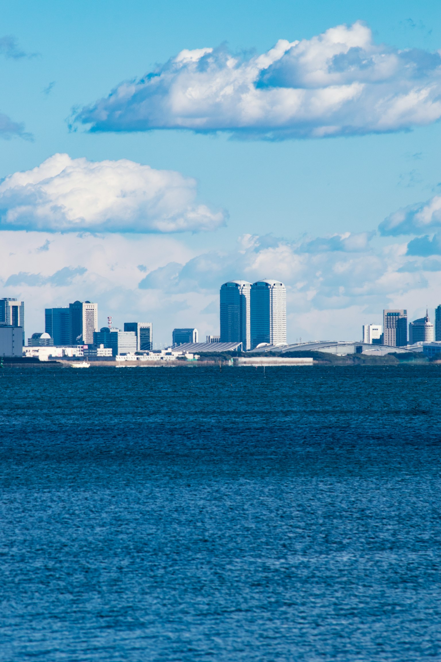 Stadtansicht vor einem blauen Ozean und wolkigem Himmel