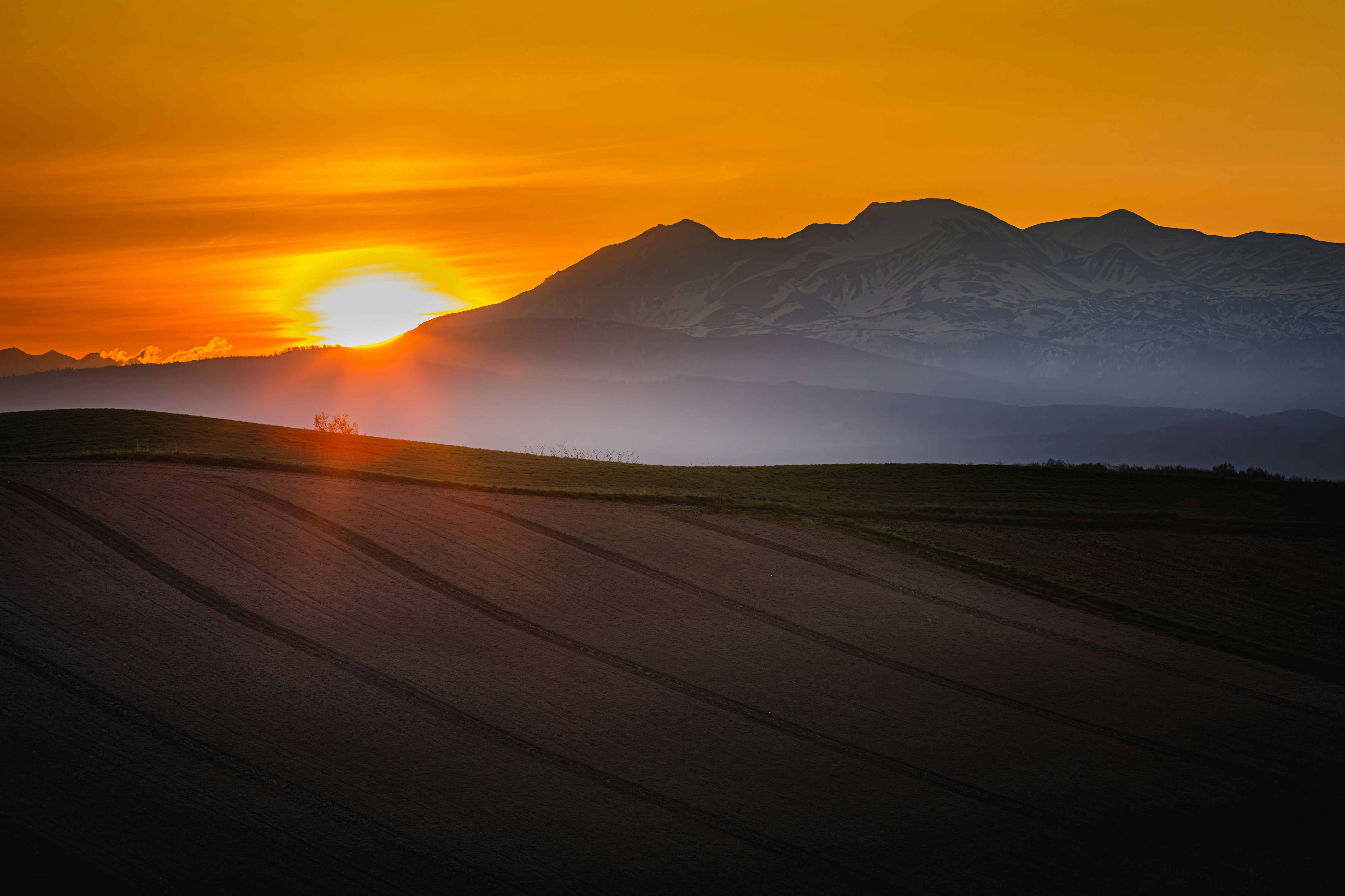 夕日に照らされた霧のかかった丘と山並みの風景