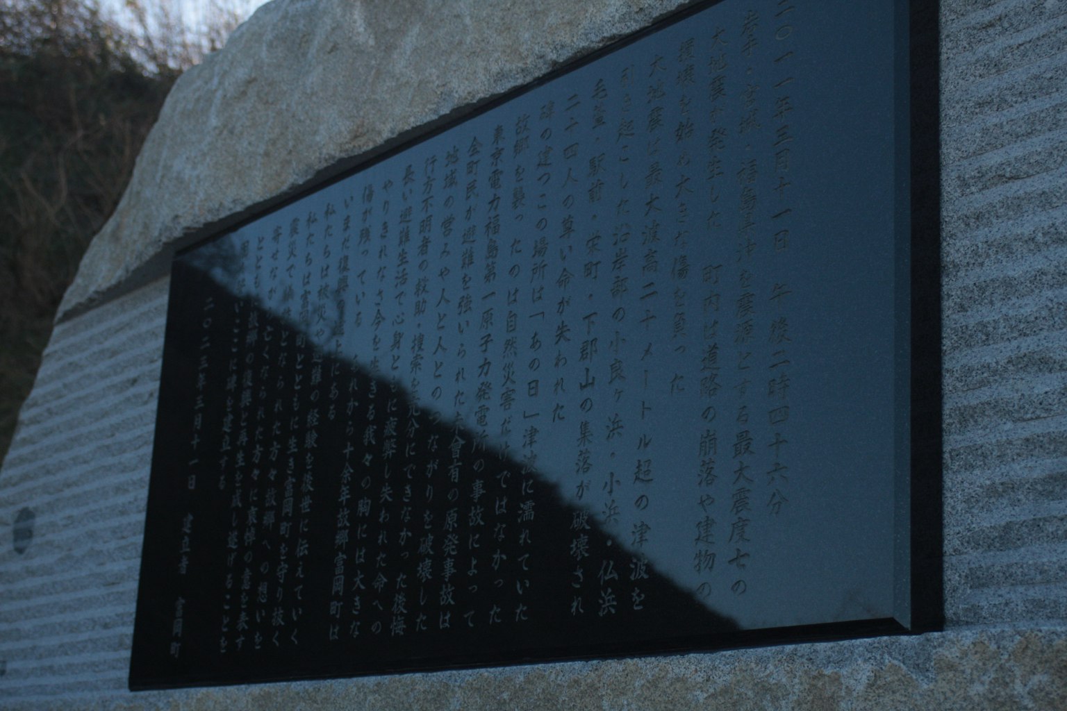 Steinmonument mit einer schwarzen Plakette, die mit Text graviert ist