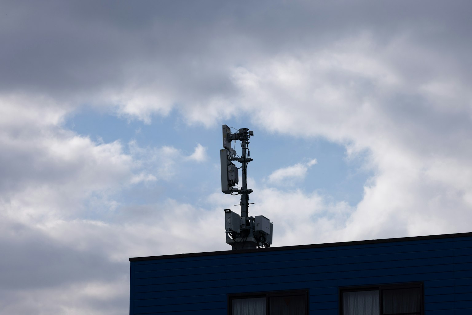 藍色建築上的通信塔和多雲的天空