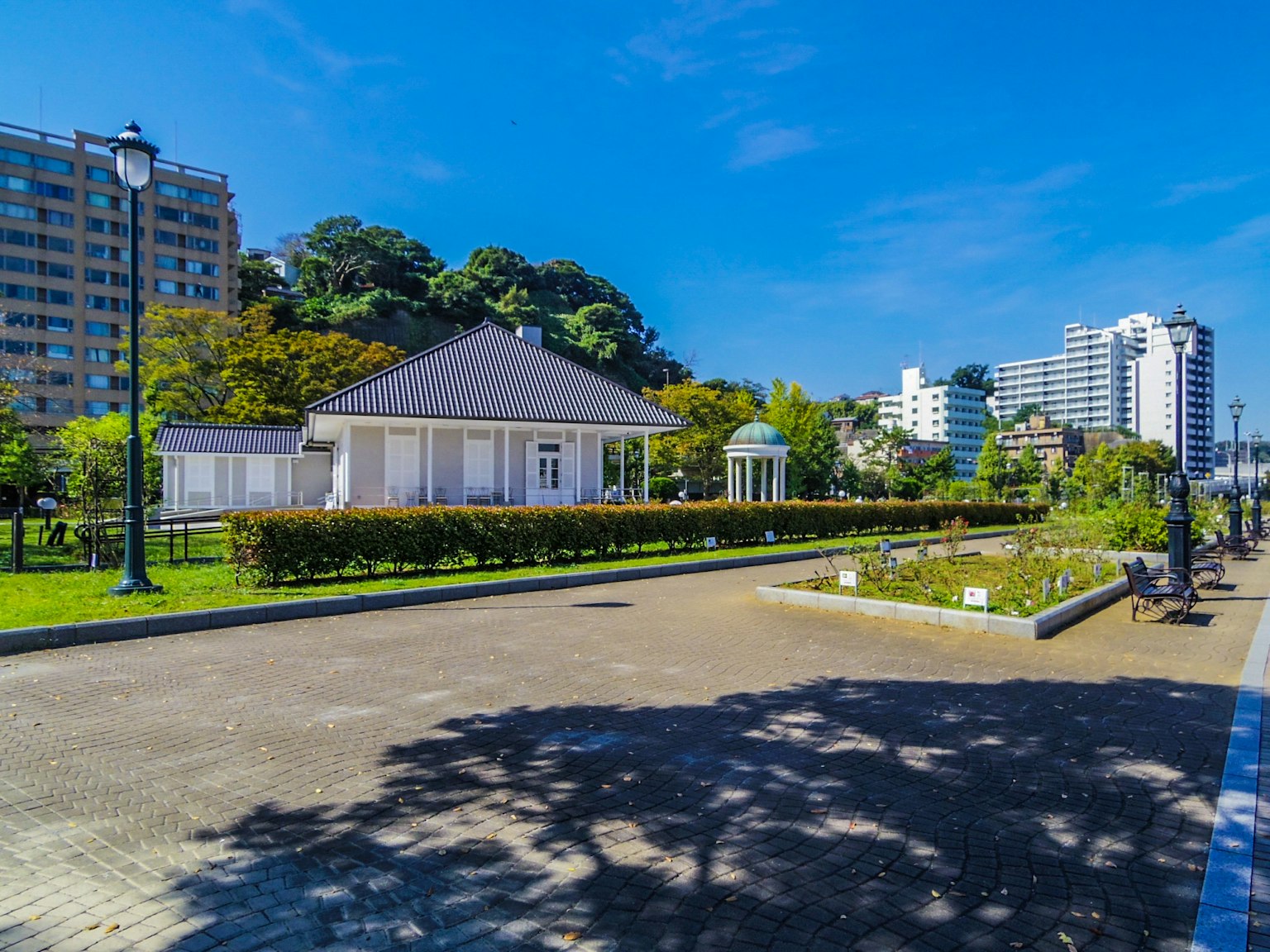 Parkszene mit einem weißen Gebäude und blauem Himmel Gärten und Wolkenkratzern