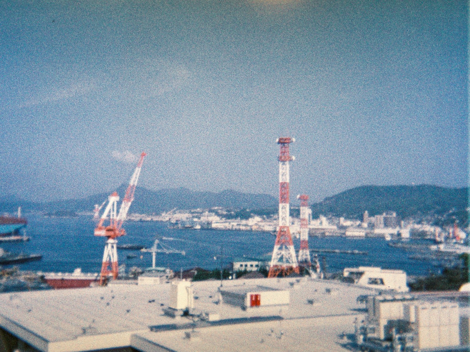 ทิวทัศน์ที่มีเครนแดงและขาวที่ท่าเรือและภูเขารอบข้าง