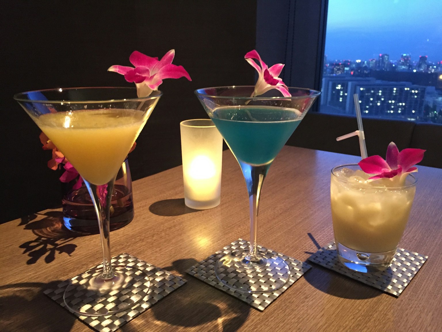 Cocktails colorés disposés sur une table près d'une fenêtre avec vue sur la ville